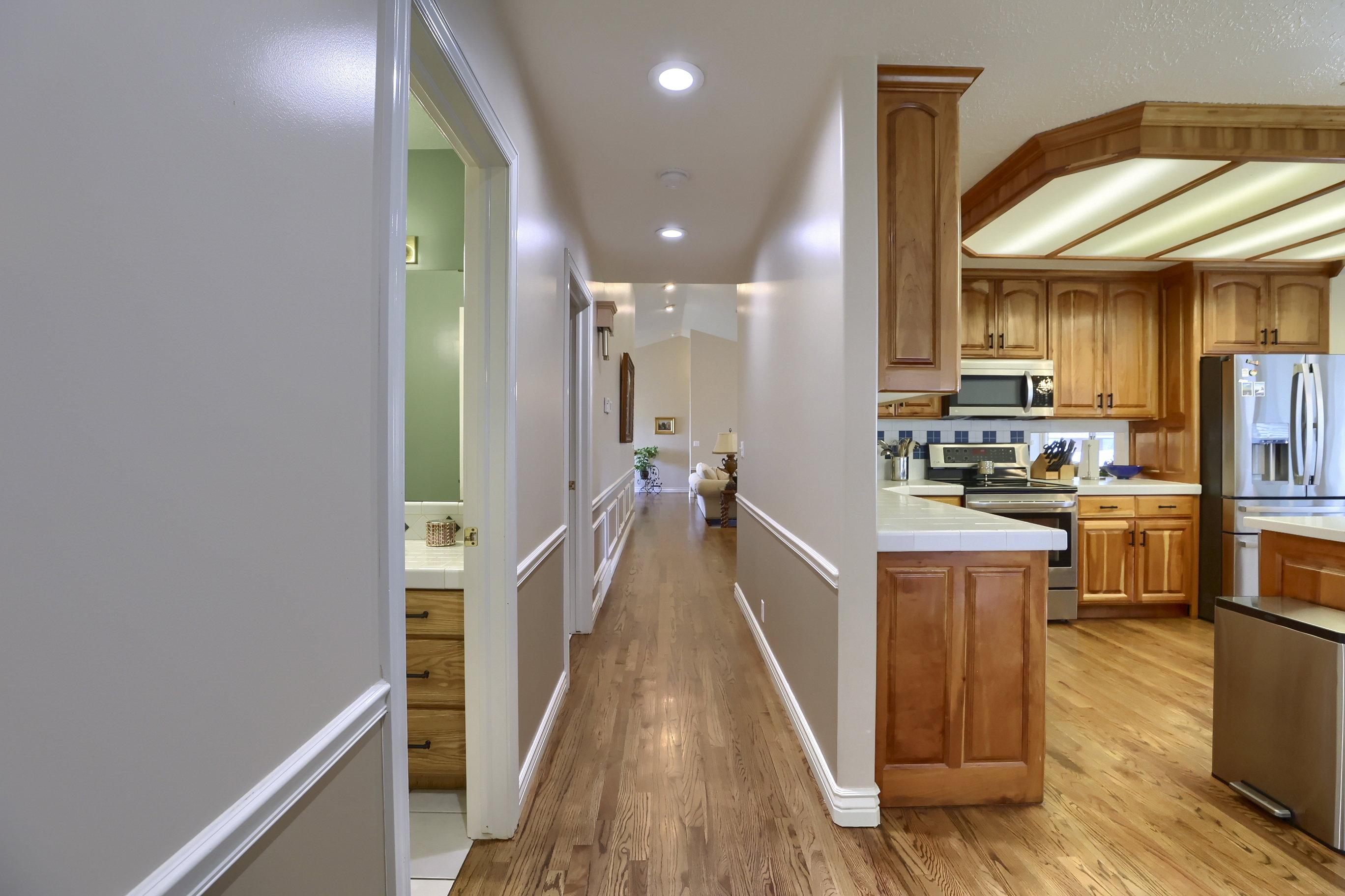 Hallway with wood-finish flooring, recessed lighting, and wainscoting detail