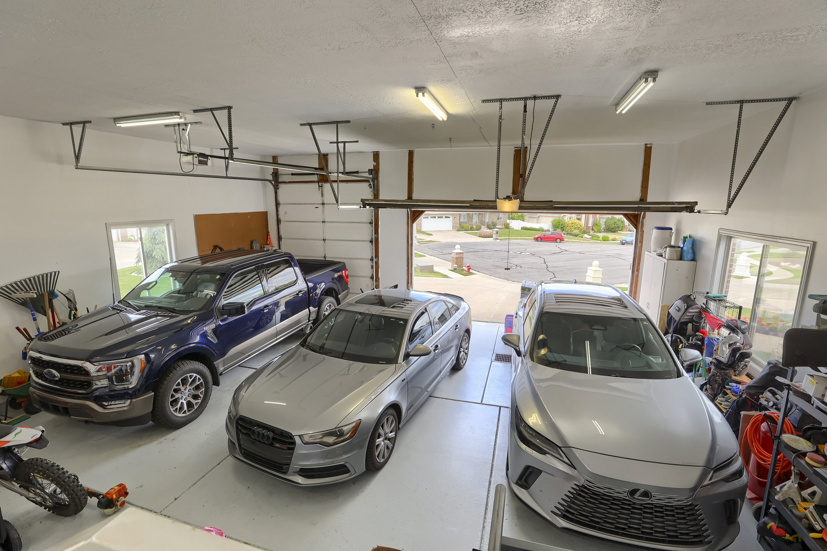 Spacious garage featuring white painted walls, exposed ceiling joists, and a light gray concrete floor