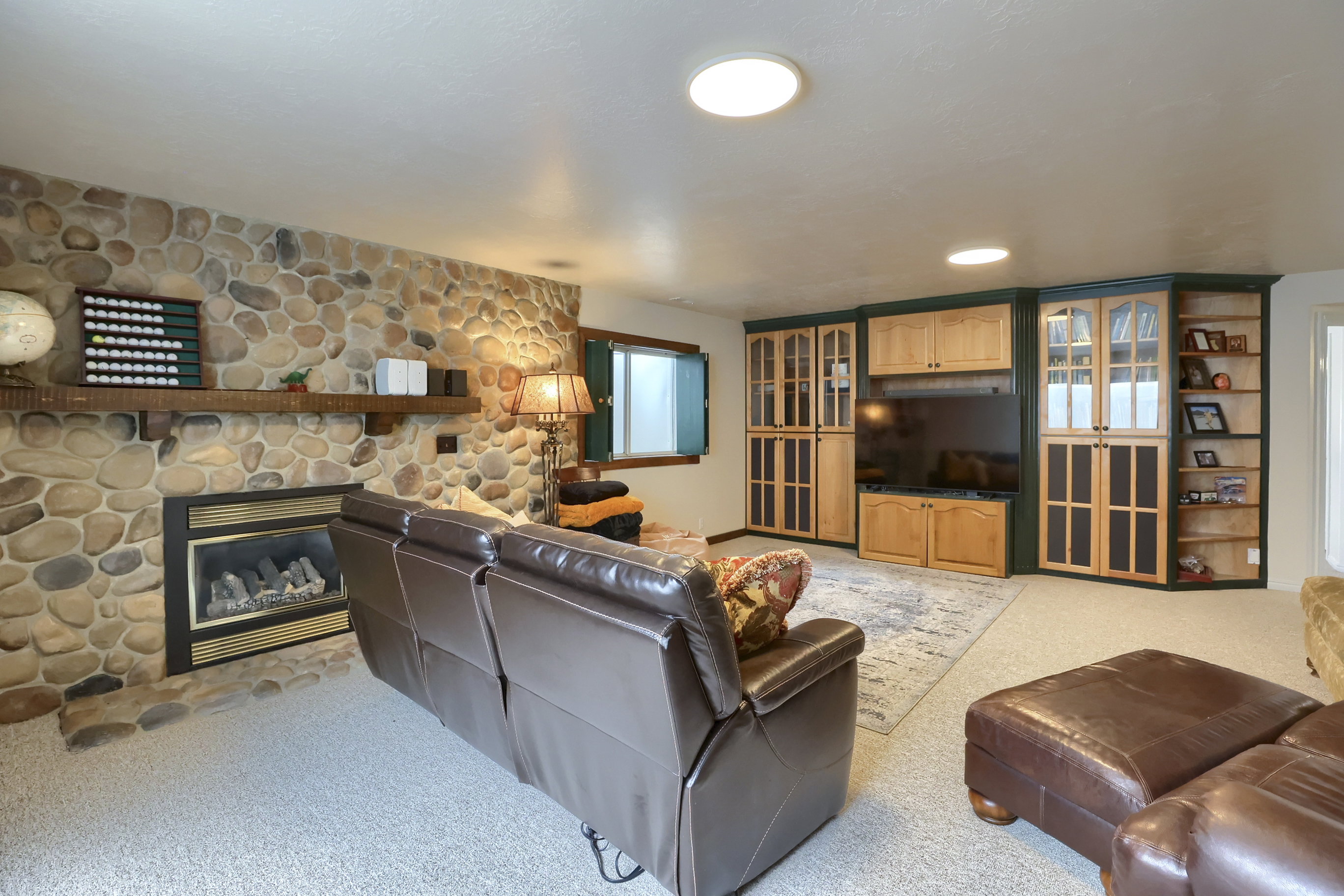 Living area featuring a floor-to-ceiling river stone accent wall with an integrated fireplace and rustic wood mantel