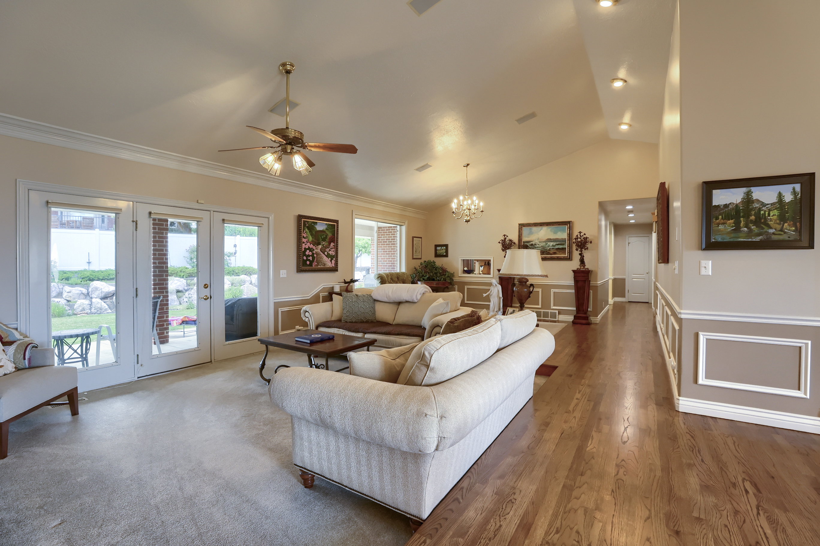 Vaulted ceiling living room featuring wood-finish flooring, recessed lighting, and crown molding