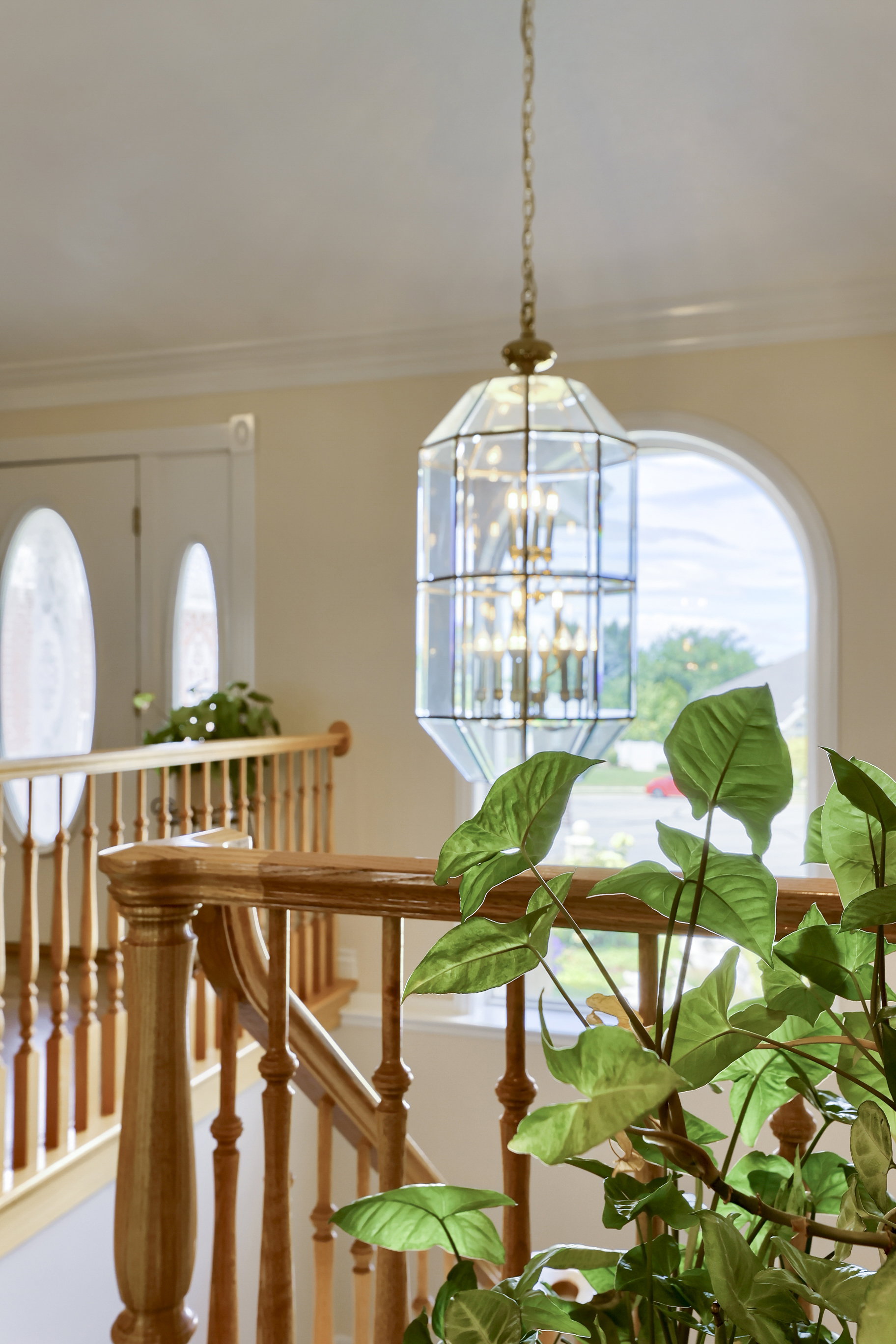 Foyer featuring a multi-tiered glass and brass chandelier, curved wooden banister, and an arched window