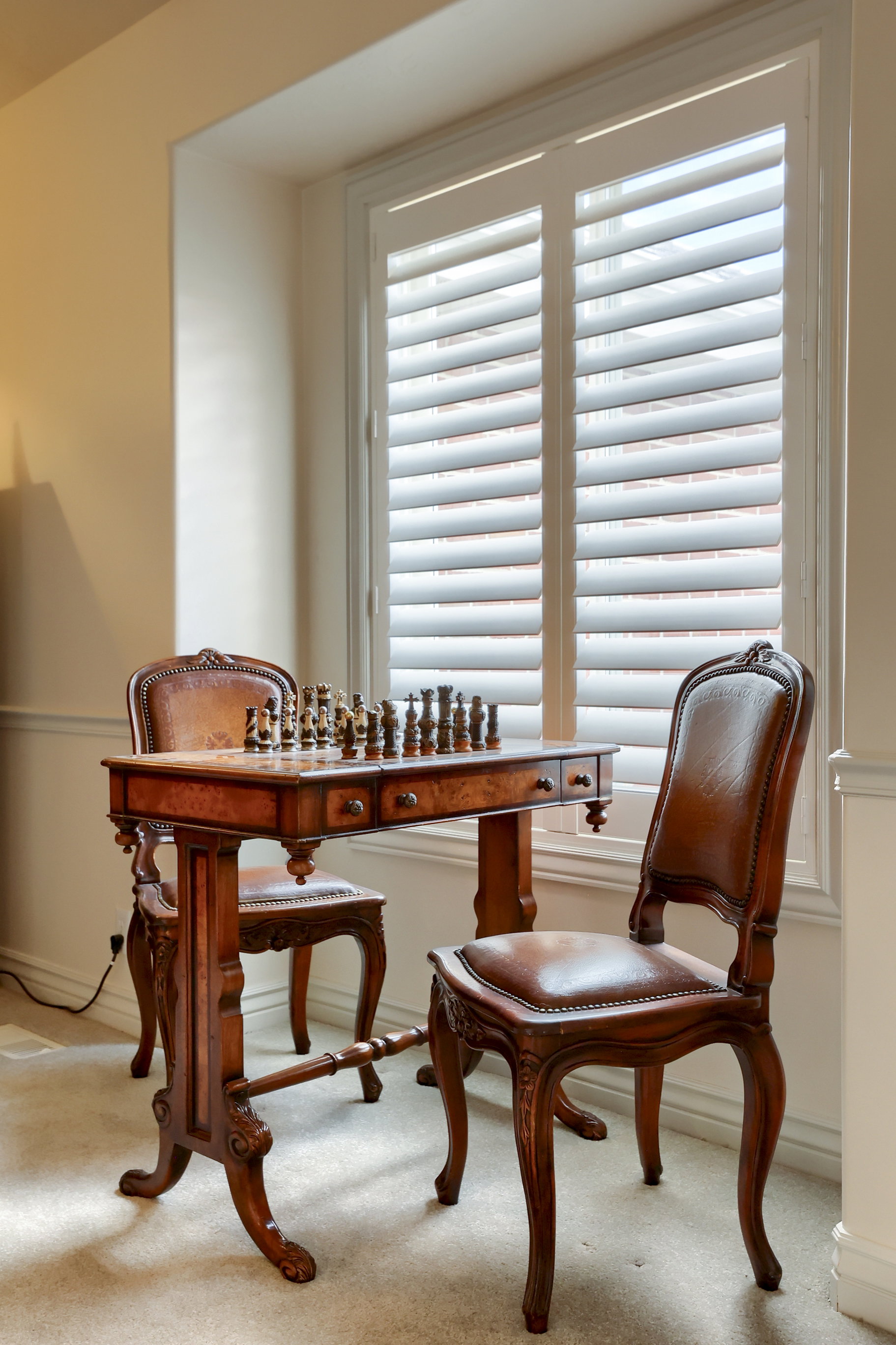 Tall window with white plantation shutters and broad window casing