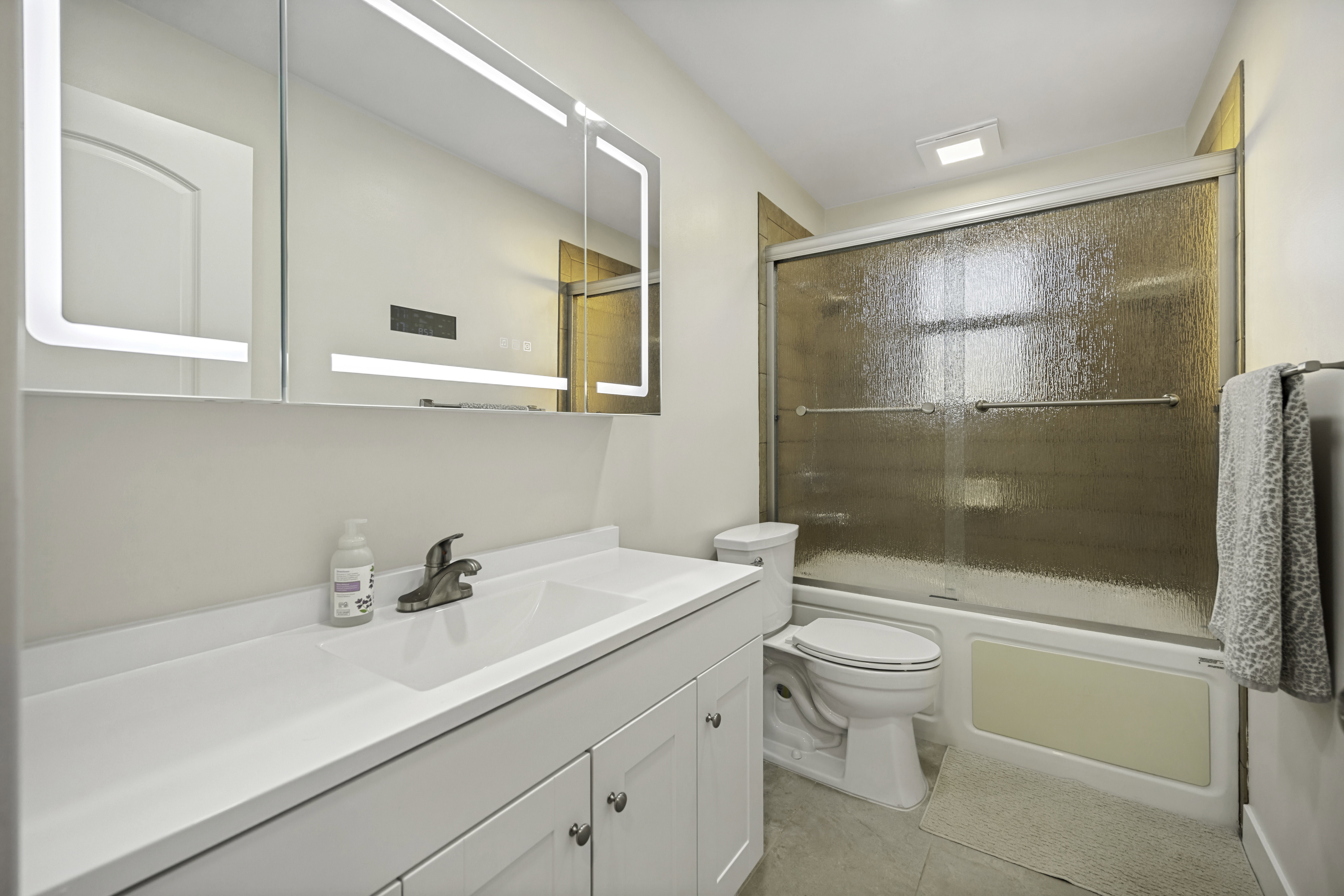 Bathroom featuring a contemporary vanity with an integrated sink, brushed nickel faucet, and an illuminated smart mirror