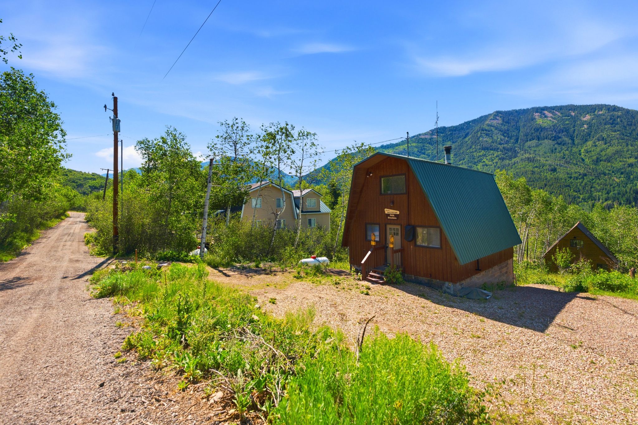 Gabled cabin-style structure featuring a metal roof, wood siding, and an elevated entrance with wood steps