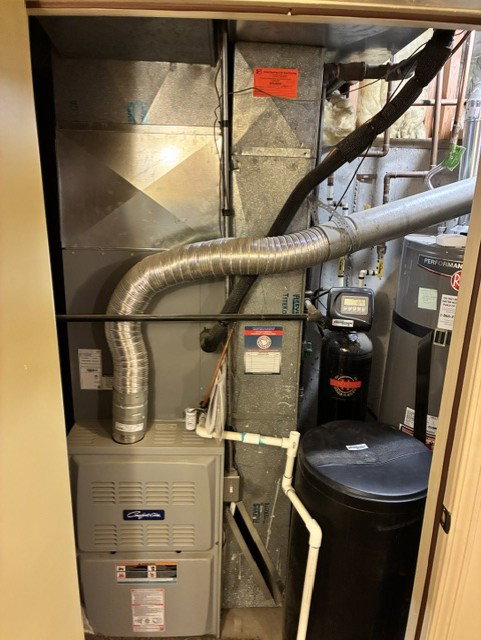 Utility closet featuring a furnace, water heater, water softener, and extensive ductwork