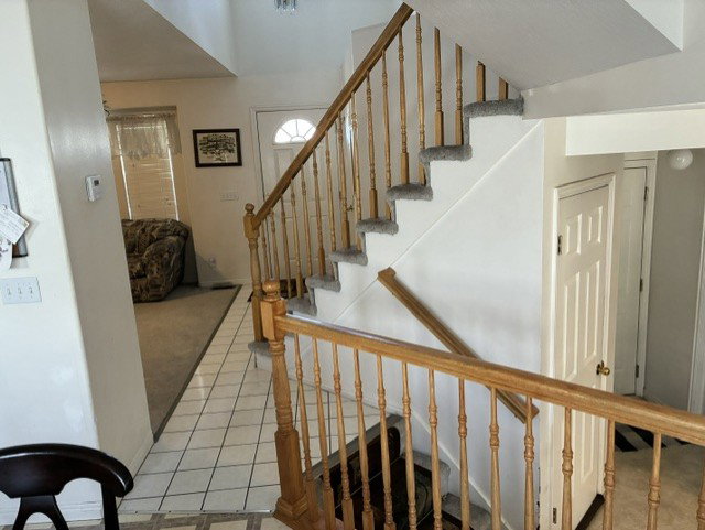 Two-story entryway featuring a wood-finish staircase with carpeted treads