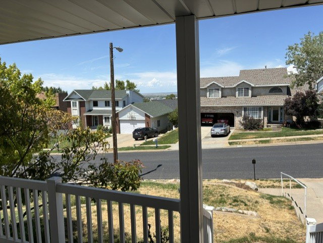 Front porch with white railings overlooking a residential street