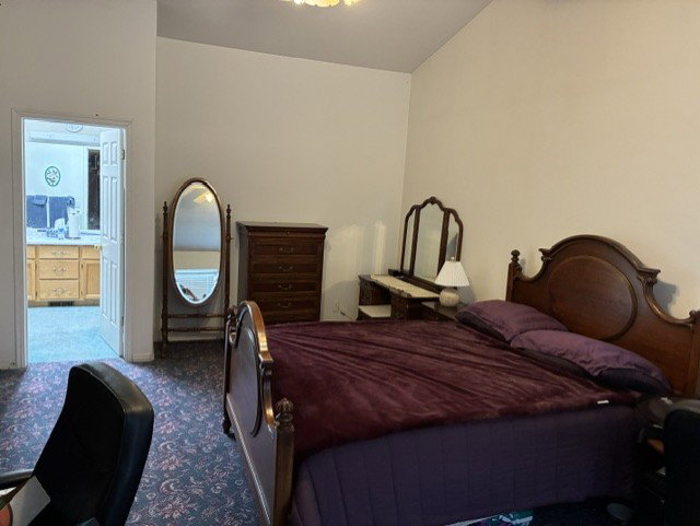 Carpeted room with a doorway leading to a separate area featuring wood-finish cabinetry and a countertop