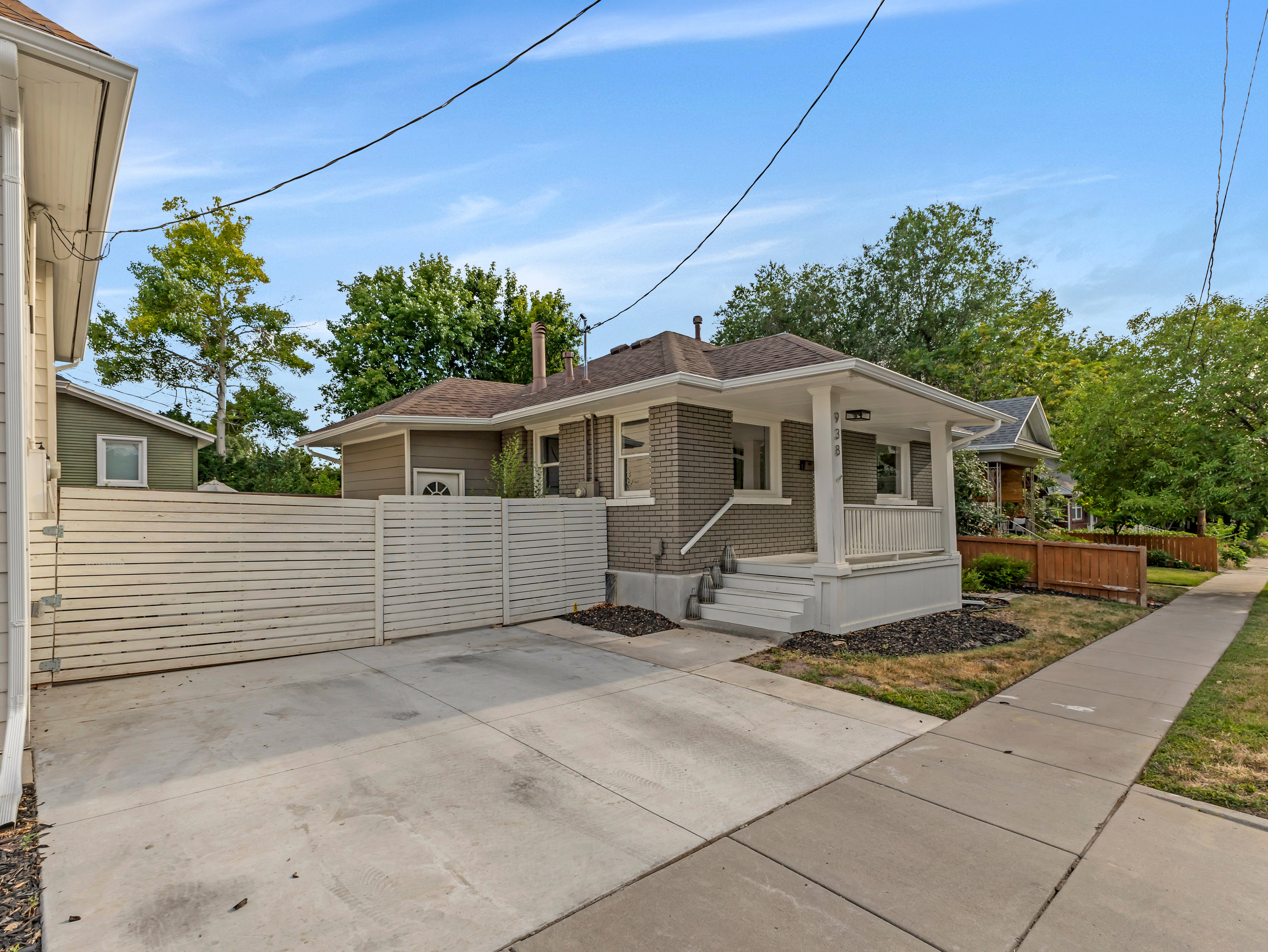 Exterior showcasing a brick facade, covered porch with white columns, and a concrete driveway