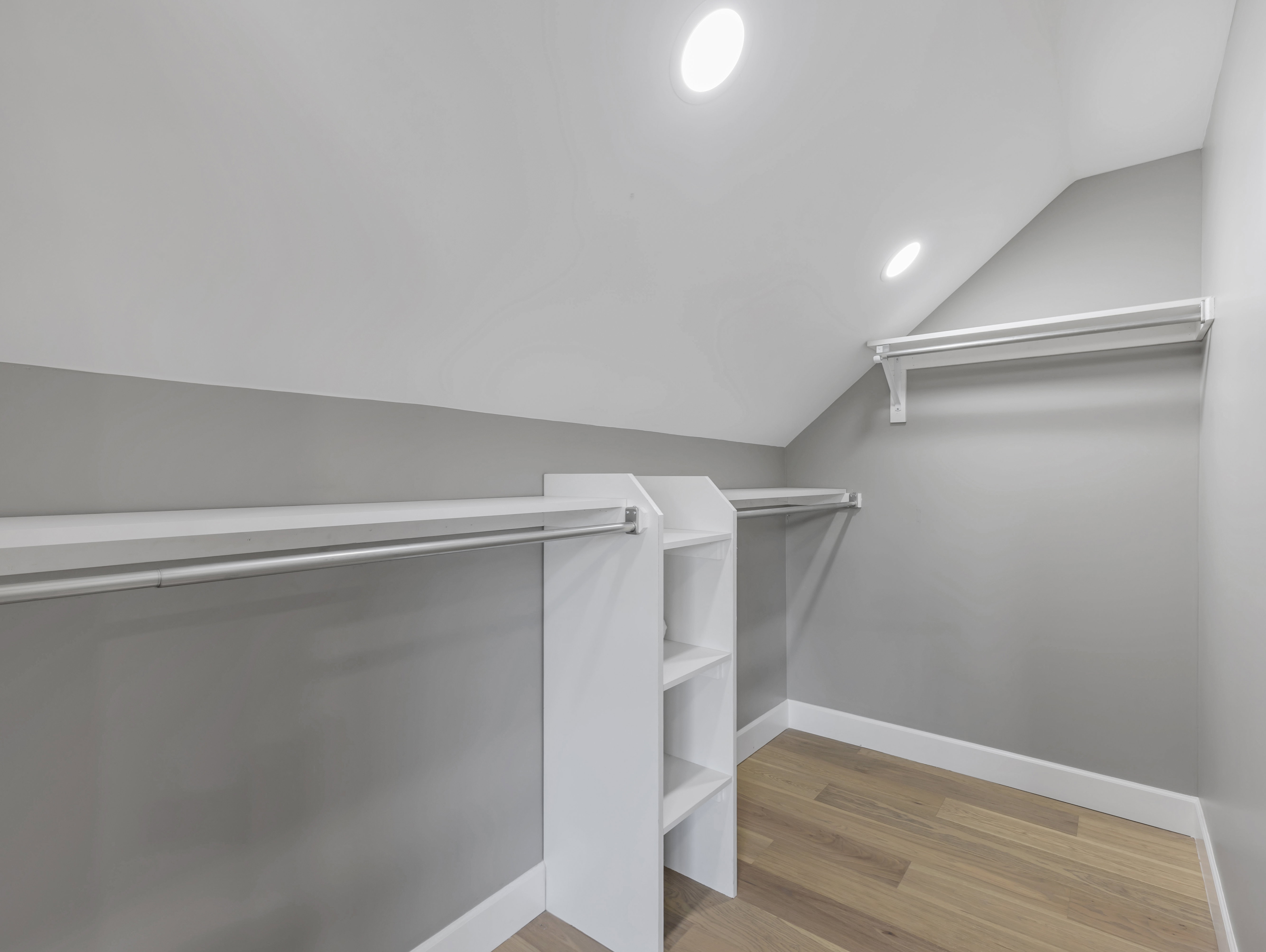 Walk-in closet featuring built-in shelving, white baseboards, wood-finish flooring, and recessed ceiling lighting