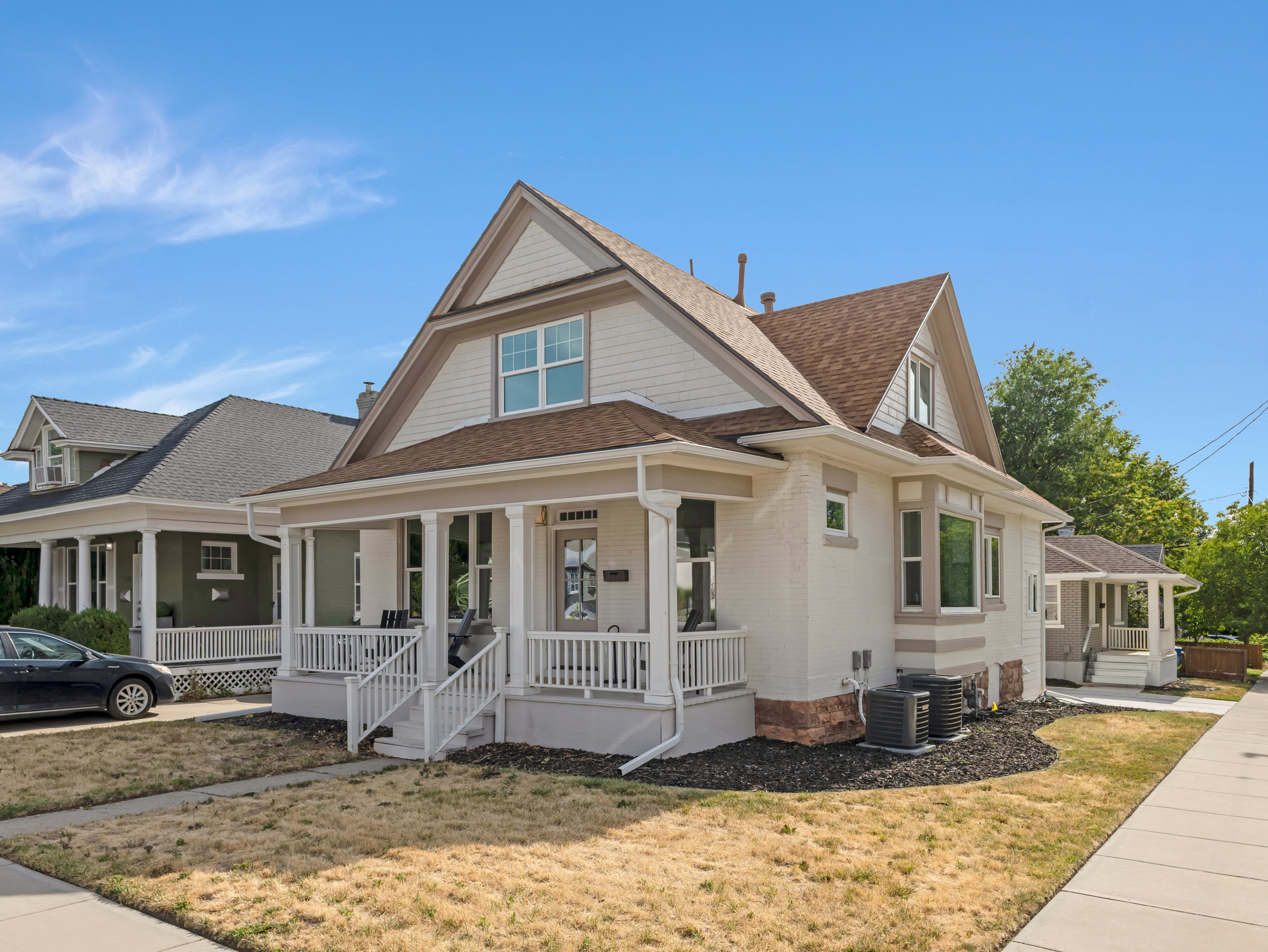 Craftsman-style home featuring a covered front porch, light-colored brick exterior, and a prominent gable roof