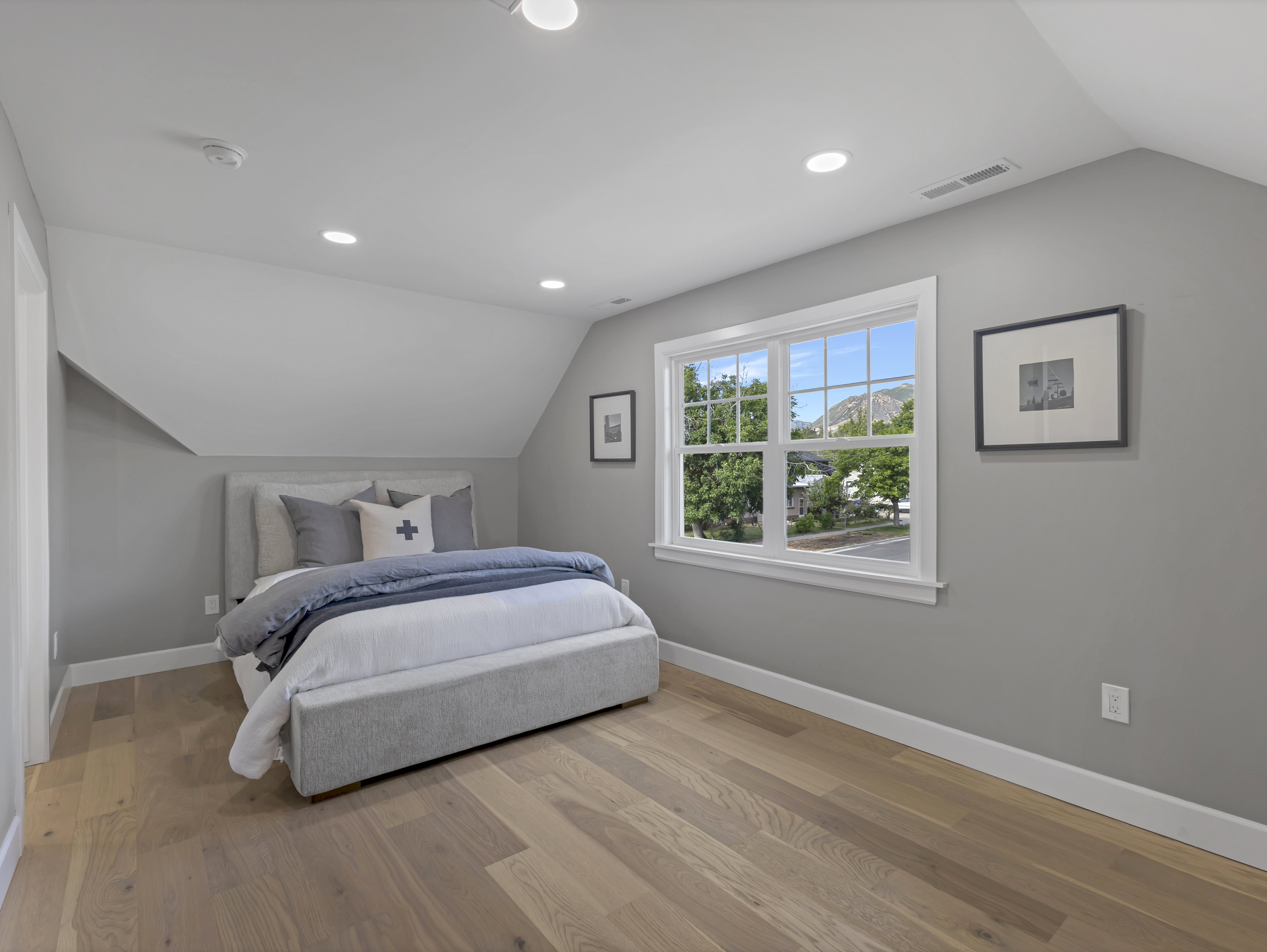 Spacious room featuring wood-finish flooring, a double window with white trim, and recessed lighting