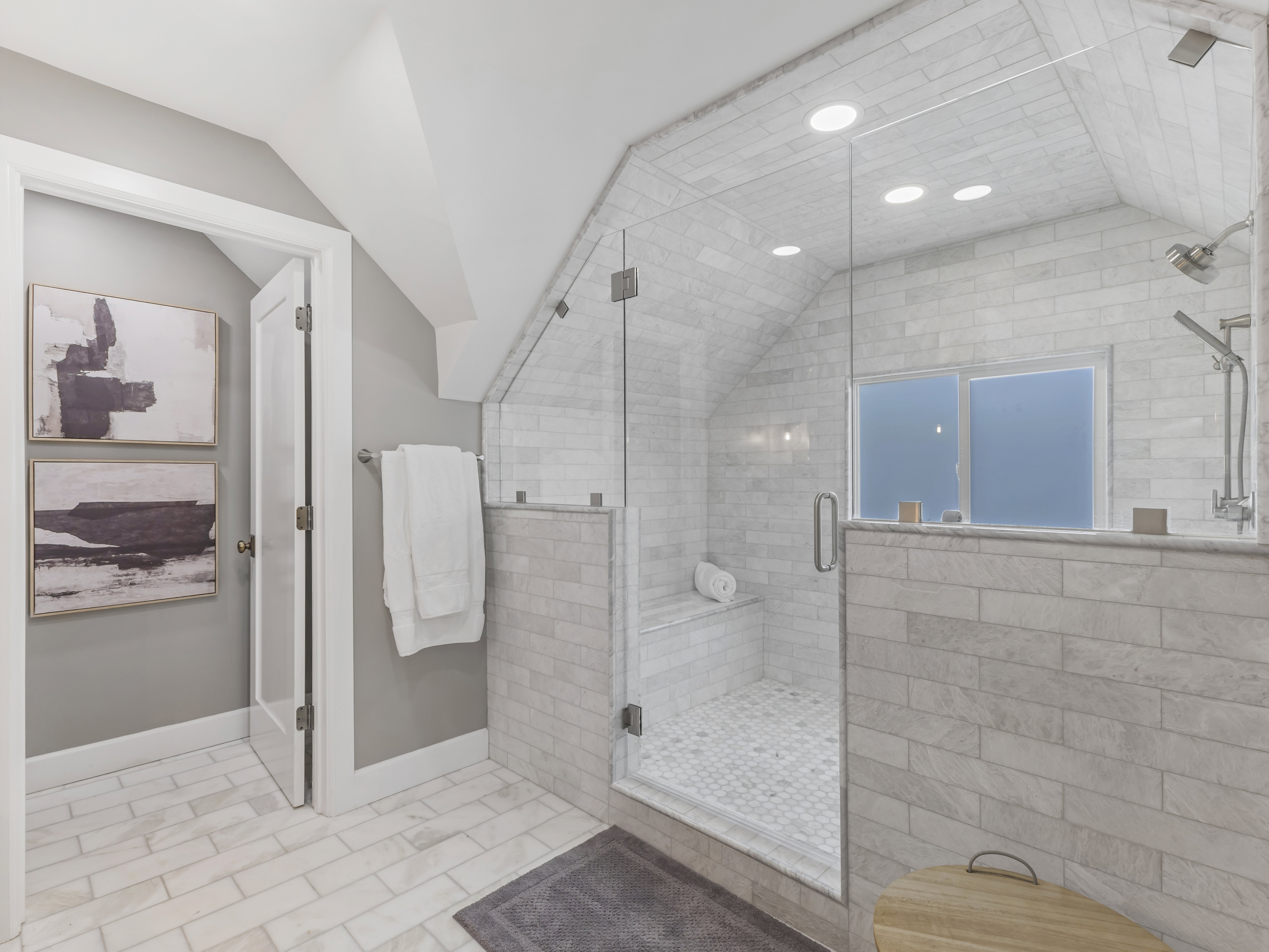Spacious bathroom featuring a glass-enclosed shower with a built-in bench, full-height tile surround, and dual shower heads