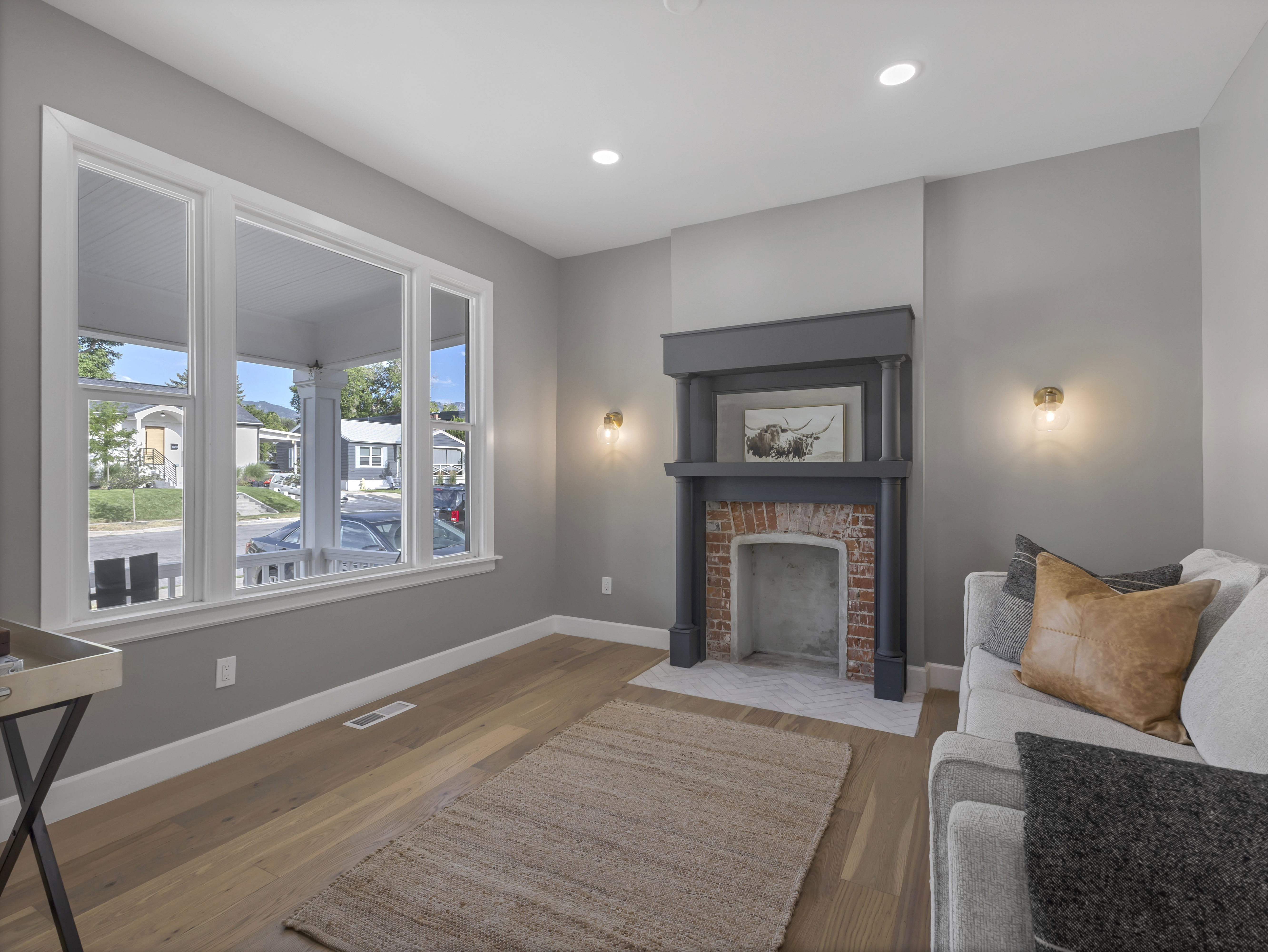 Living space featuring a decorative fireplace with a brick firebox, dark wood mantel, and herringbone tile hearth