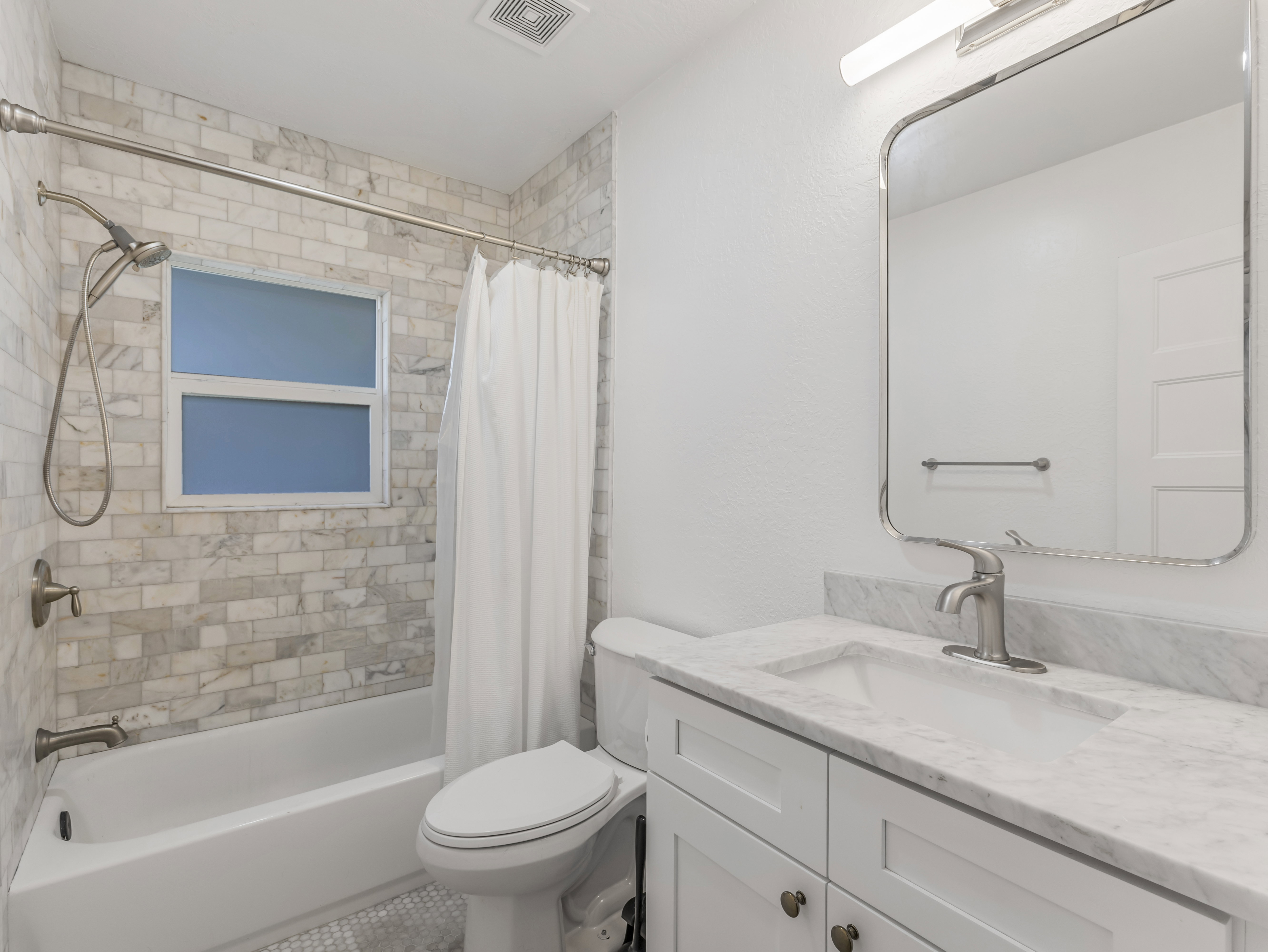 Bathroom featuring a white bathtub, subway tile shower surround, and a vanity with a stone countertop