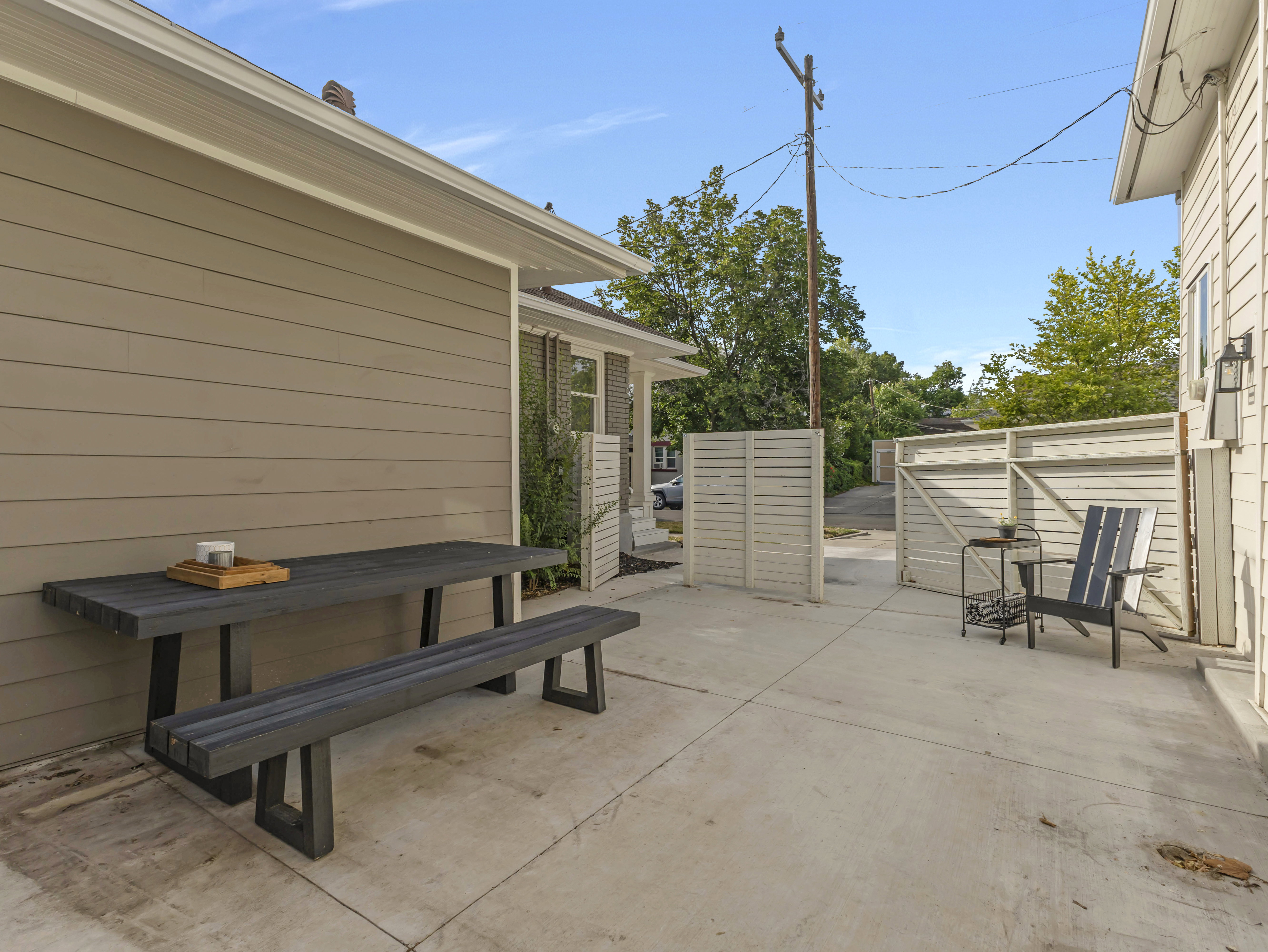 Concrete patio area featuring a slatted privacy fence and exterior siding