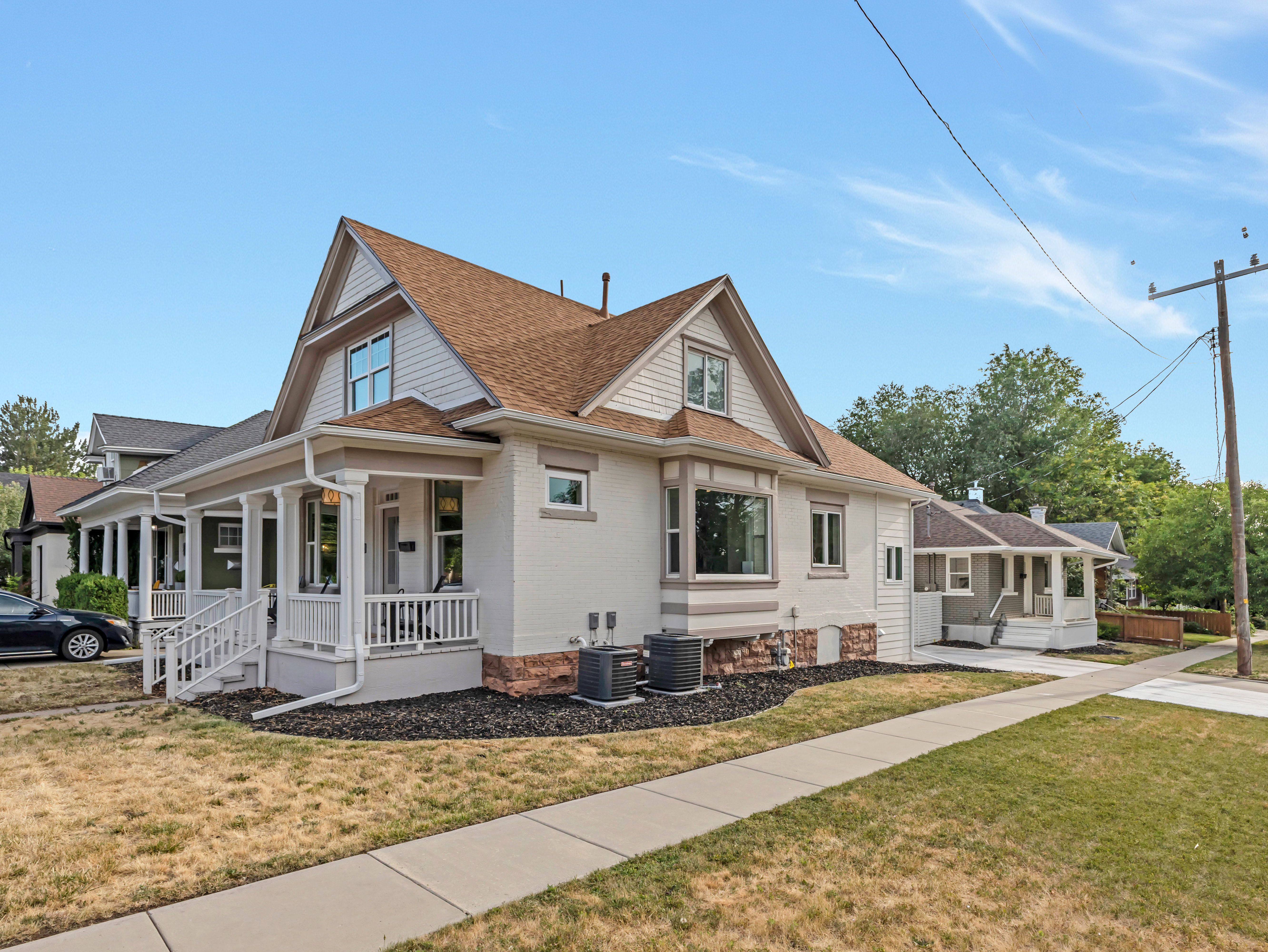 Property exterior featuring white painted brick and lap siding, a covered porch with white railing, a bay window, and a brown shingle roof