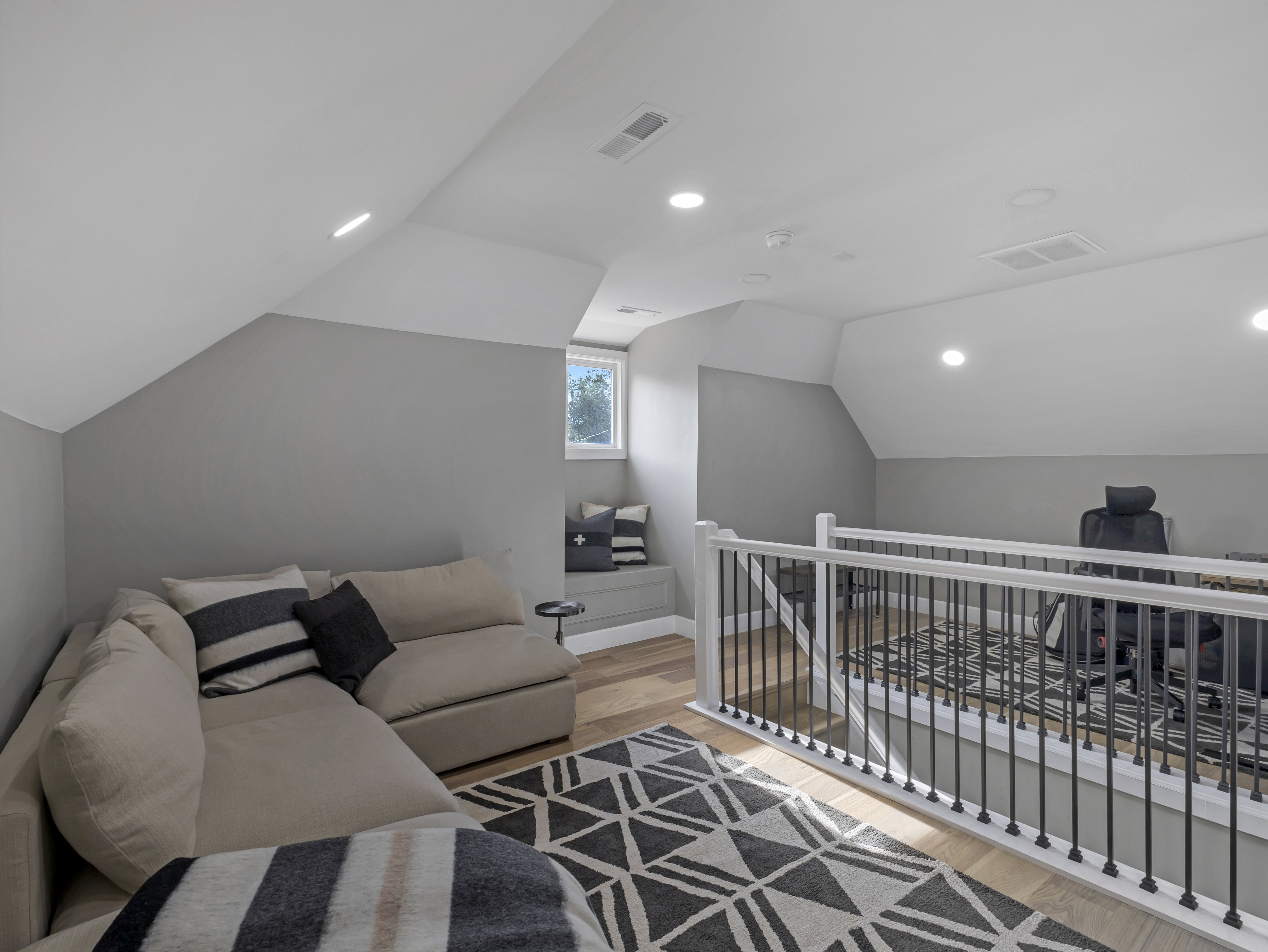 Loft space featuring wood-finish flooring, recessed lighting, and a white railing with black balusters