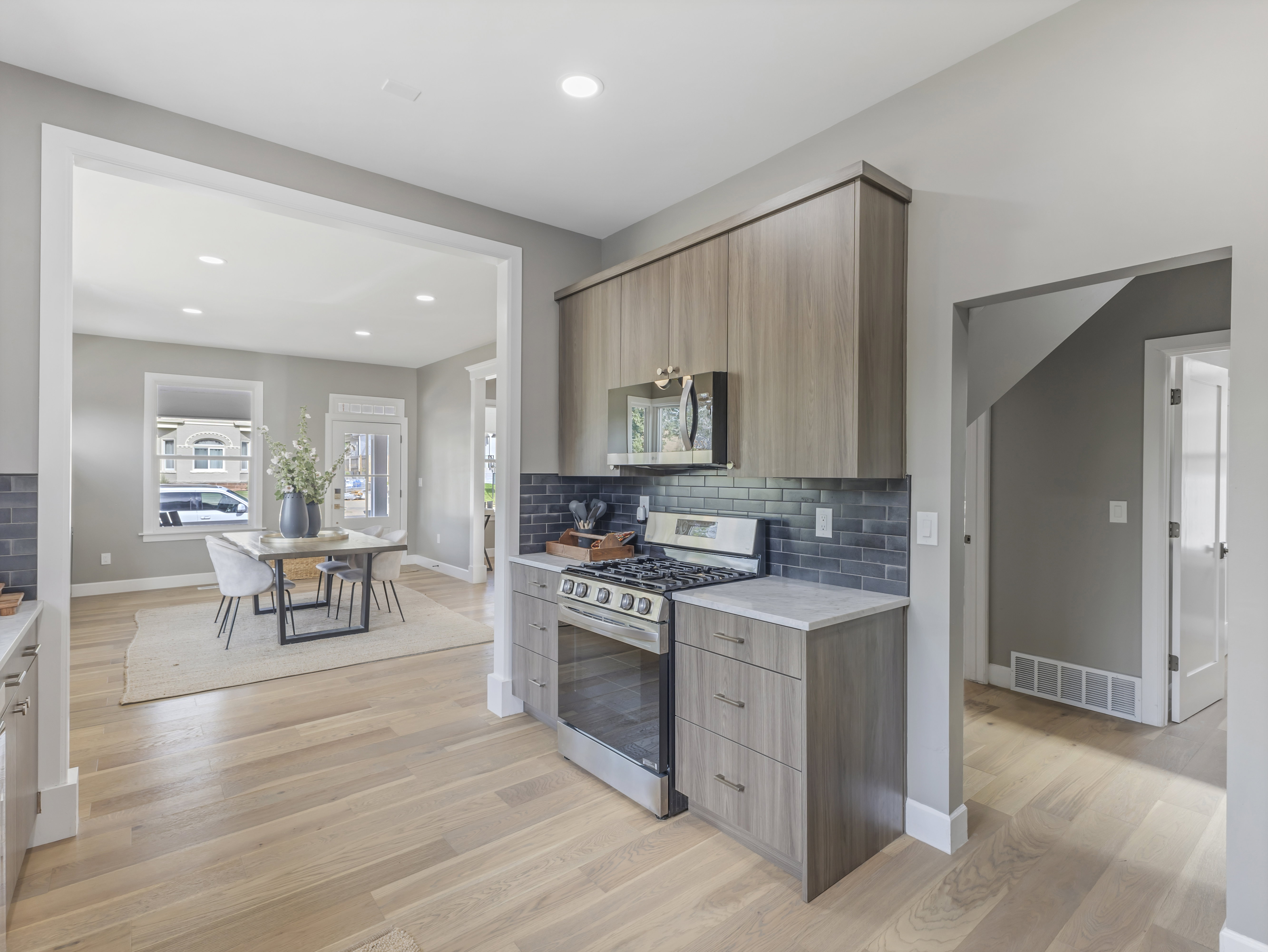 Kitchen area featuring wood-finish cabinetry, stainless steel range with overhead microwave, and a dark tile backsplash