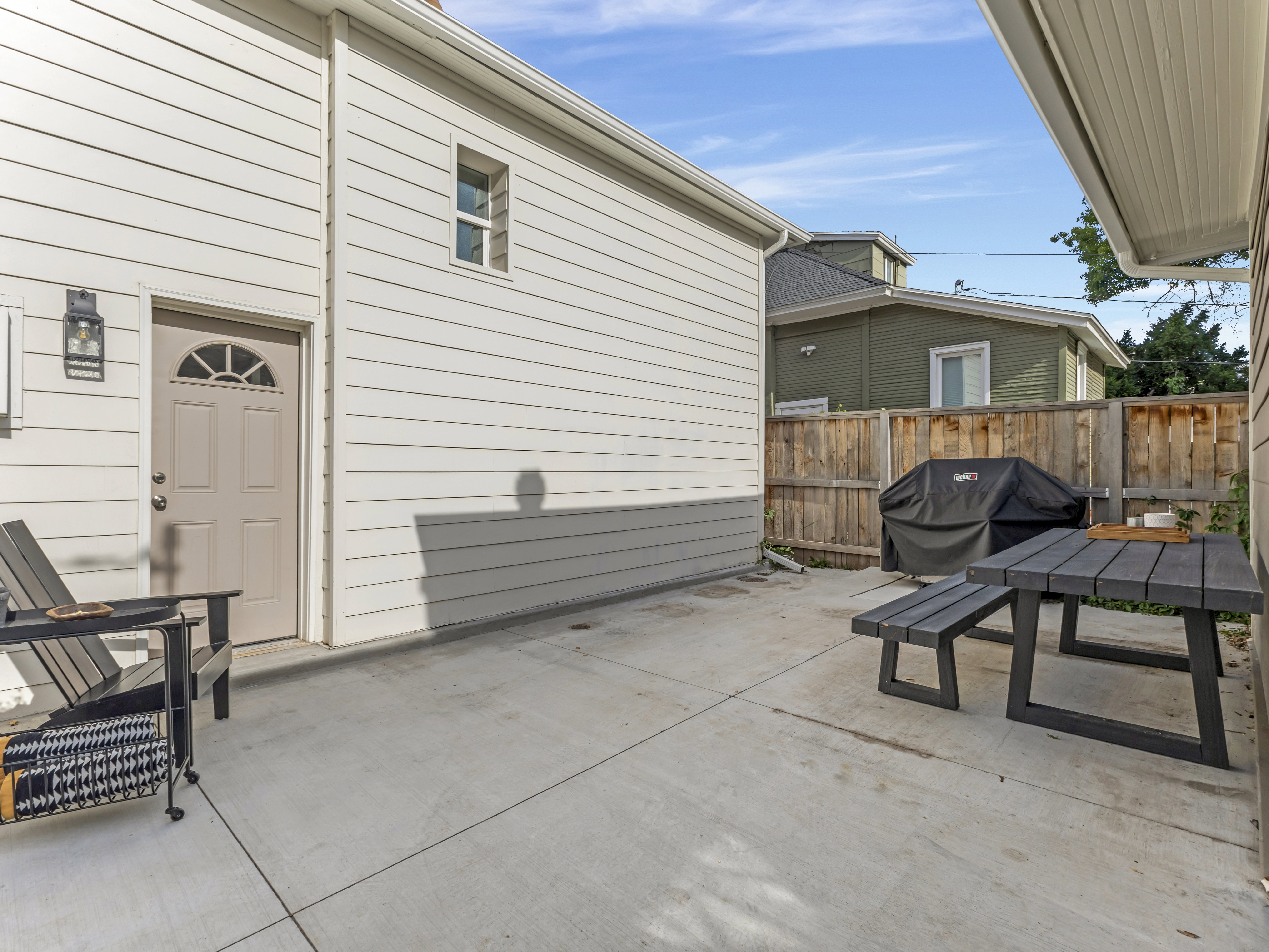 Paved patio area featuring concrete surfacing, a privacy fence, and an exterior door with an arched window insert