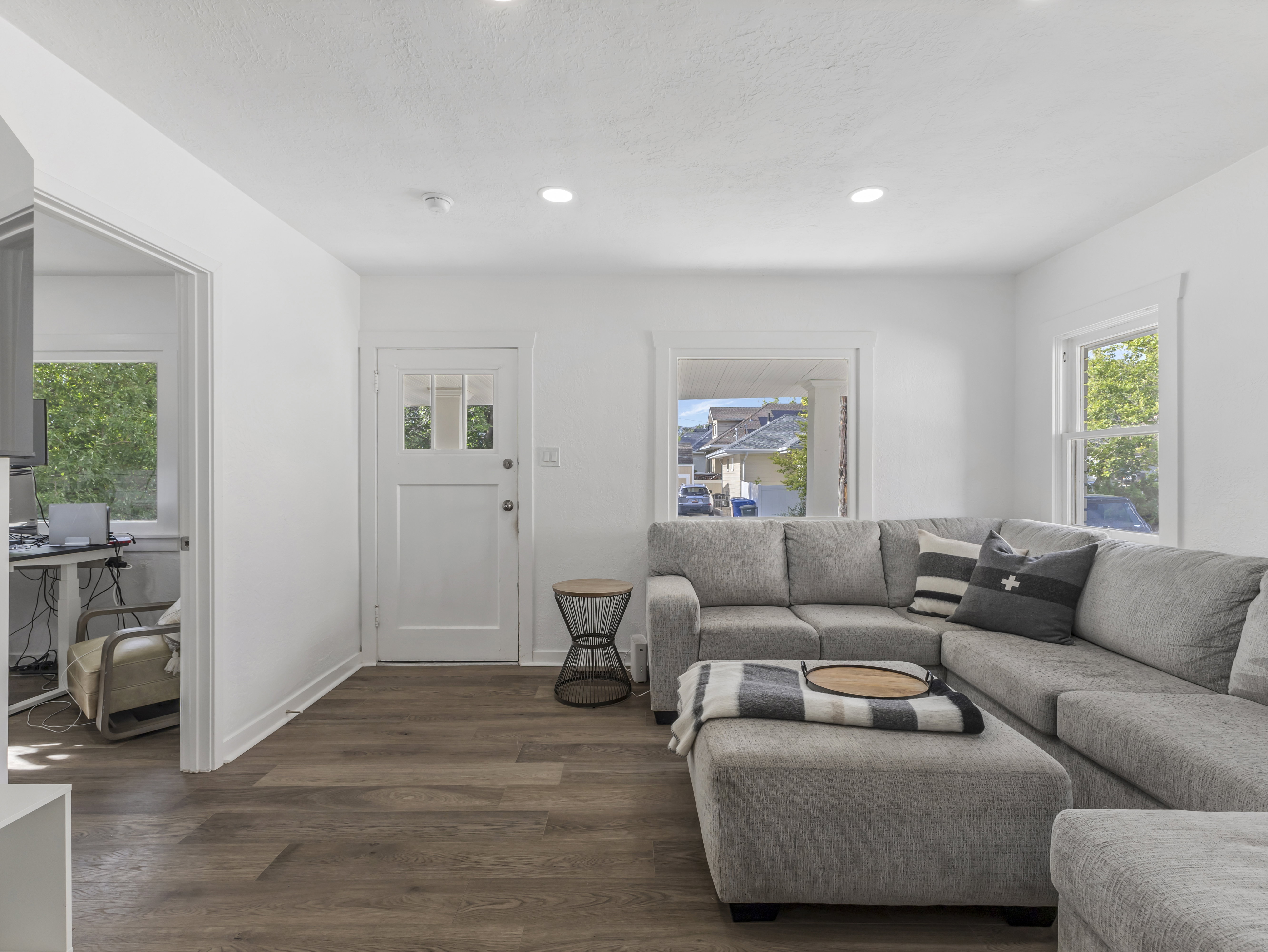 Living area featuring wood-finish flooring, recessed lighting, white walls, and a white paneled entry door with glass inserts