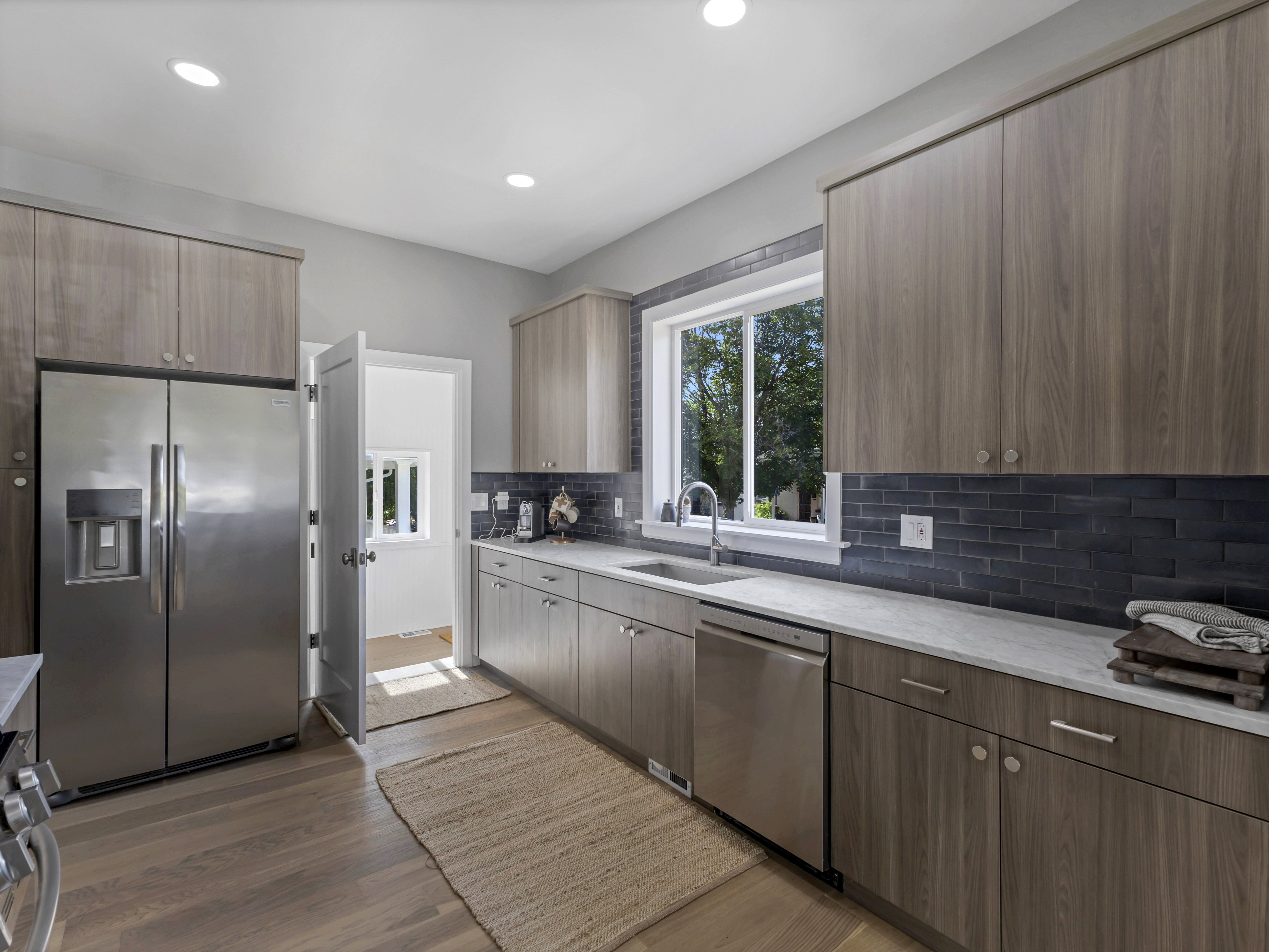Modern kitchen featuring wood-finish cabinetry, stainless steel appliances, and a dark subway tile backsplash