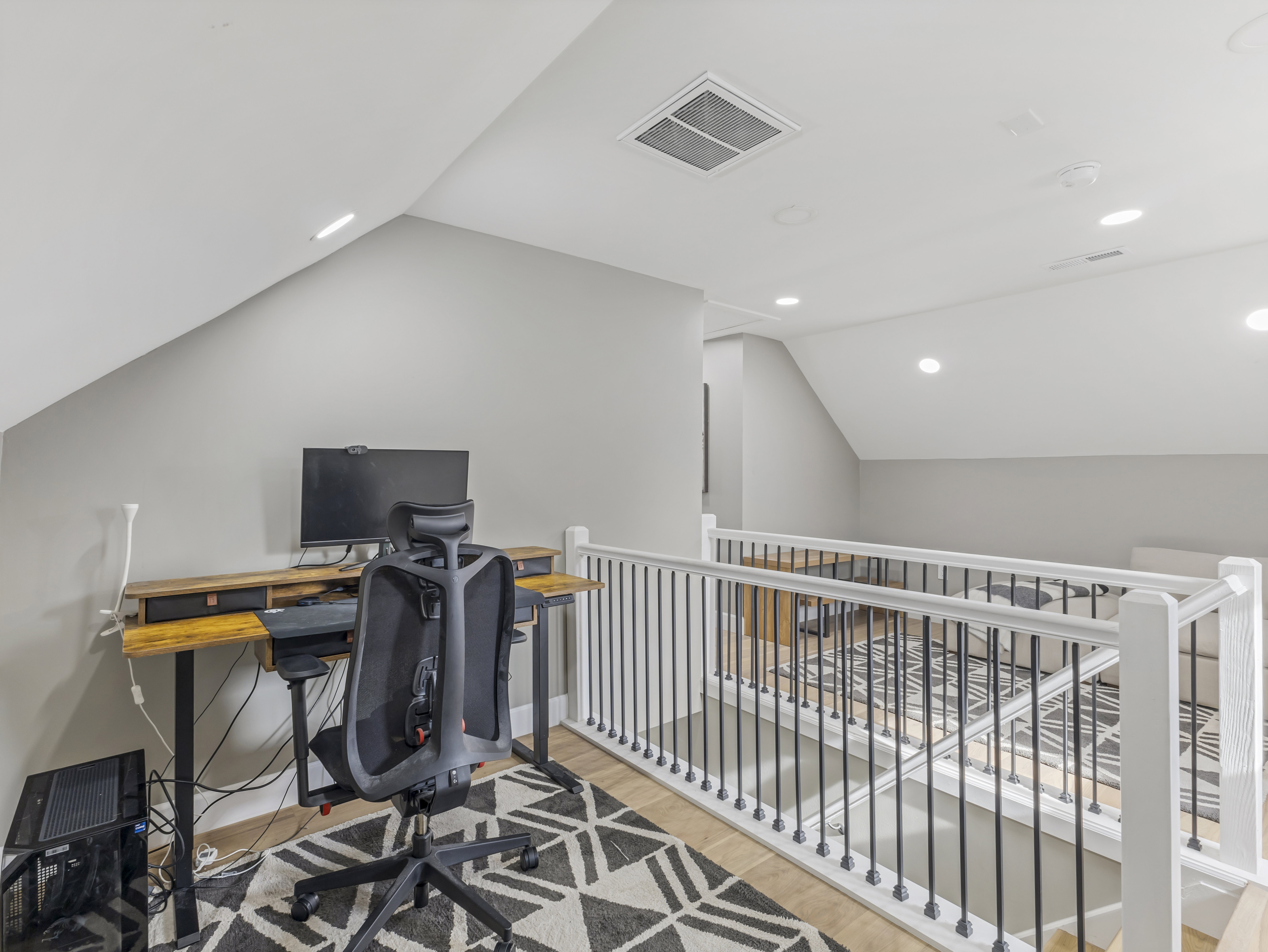 Loft area featuring vaulted ceilings, recessed lighting, wood-finish flooring, and a white railing with black balusters