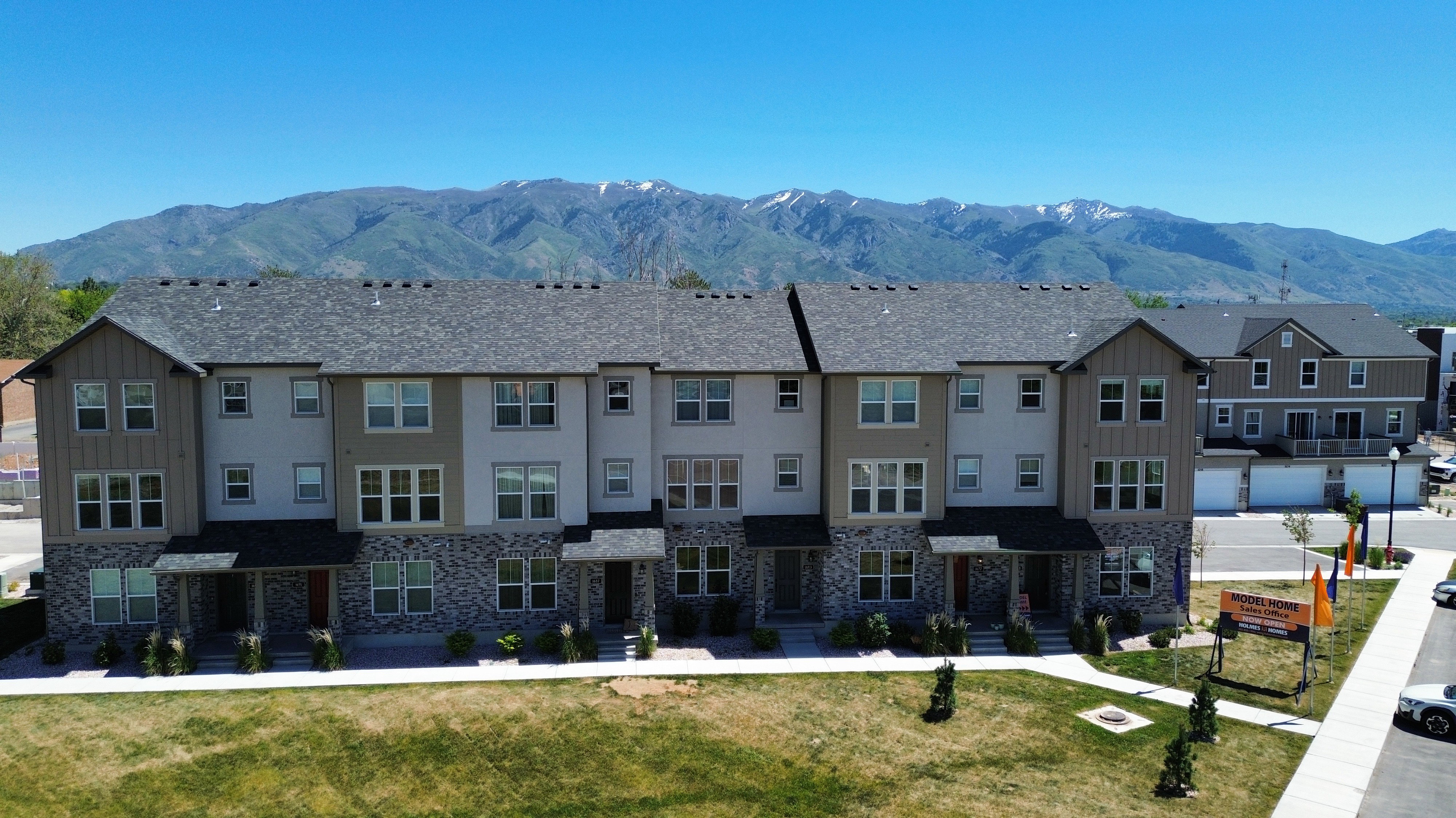 Contemporary townhome architecture featuring three stories, stone veneer, horizontal siding, and multiple windows