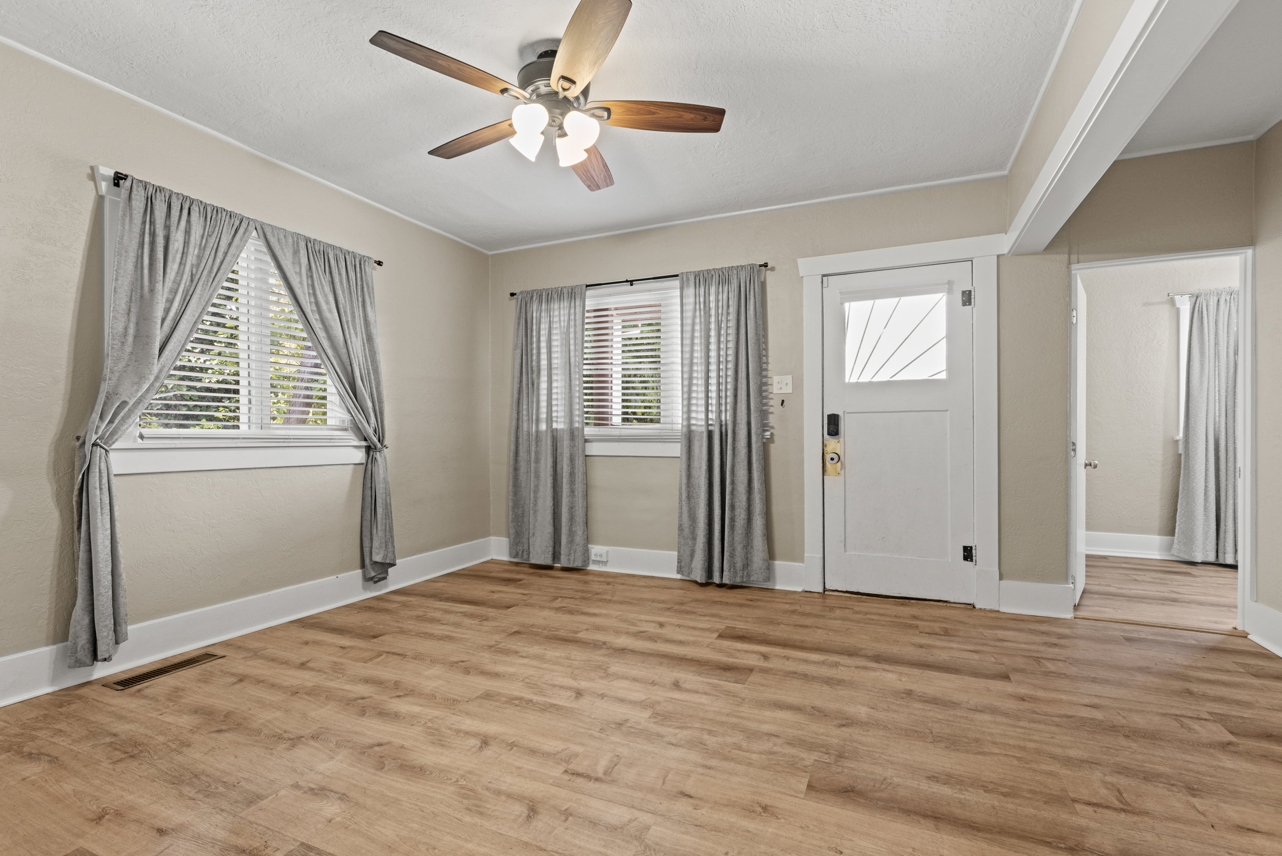 Spacious room featuring wood-finish flooring, light-toned wall paint, and white trim throughout