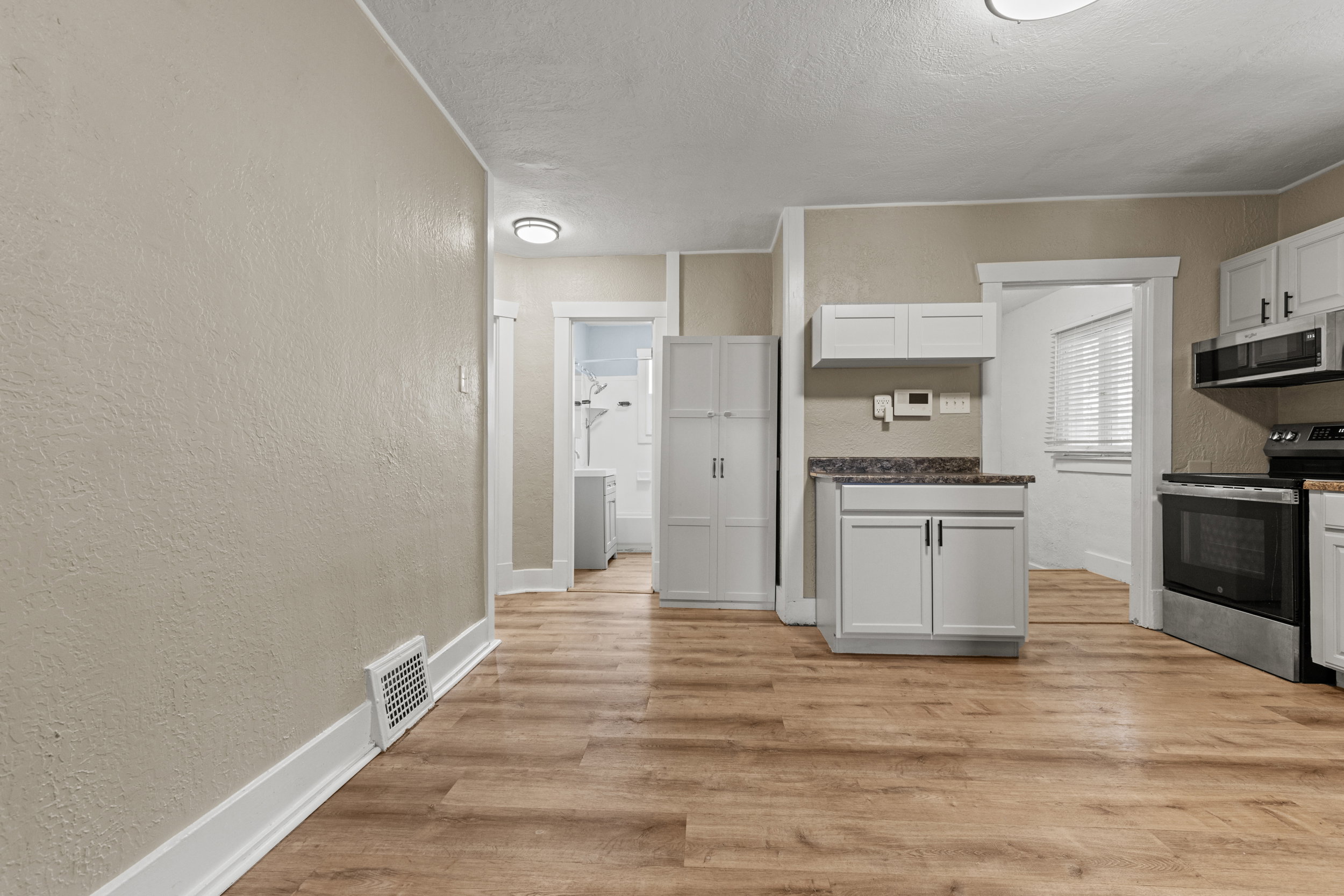 Open-concept room featuring wood-finish flooring, light-colored walls, white baseboards, and ceiling-mounted lighting