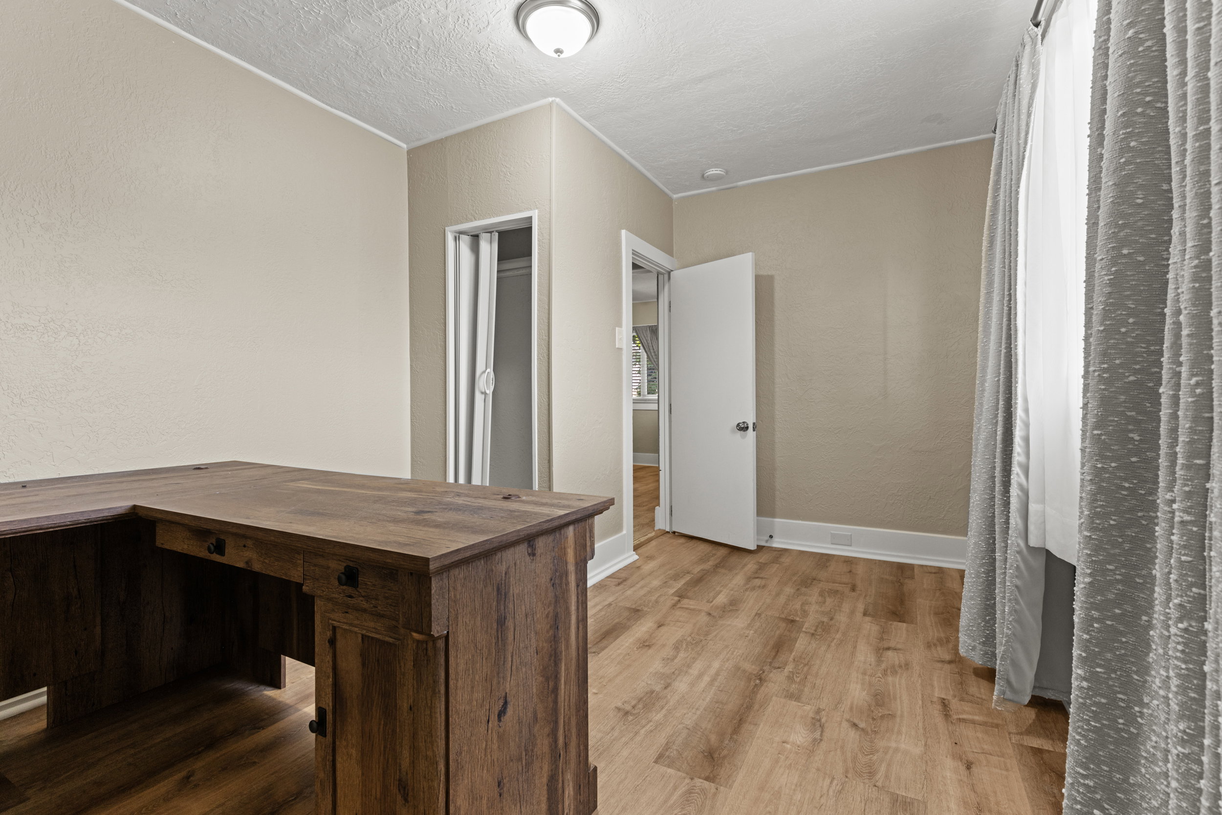 Room with wood-finish flooring, neutral wall paint, and white baseboards