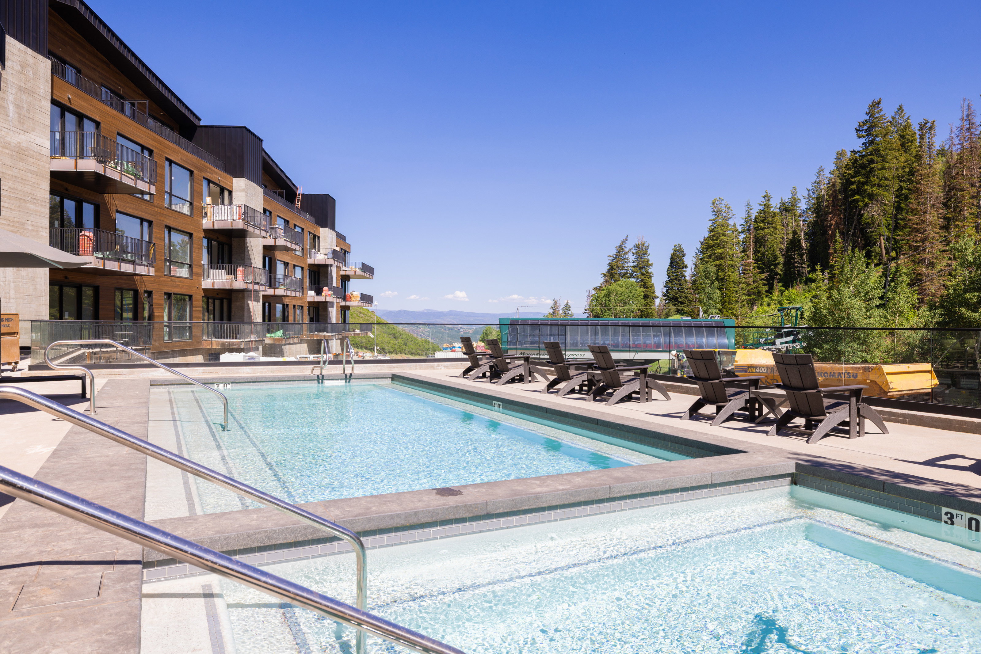 Outdoor swimming pool with integrated hot tub, surrounded by a hardscaping deck