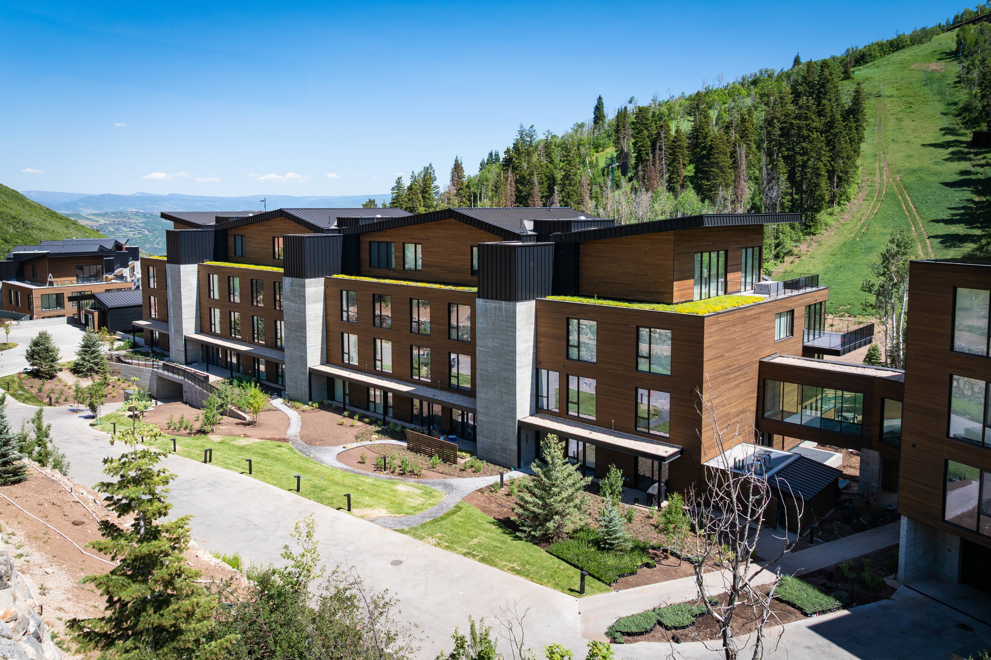 Contemporary multi-story building featuring natural wood-finish siding, dark metal accents, and concrete elements