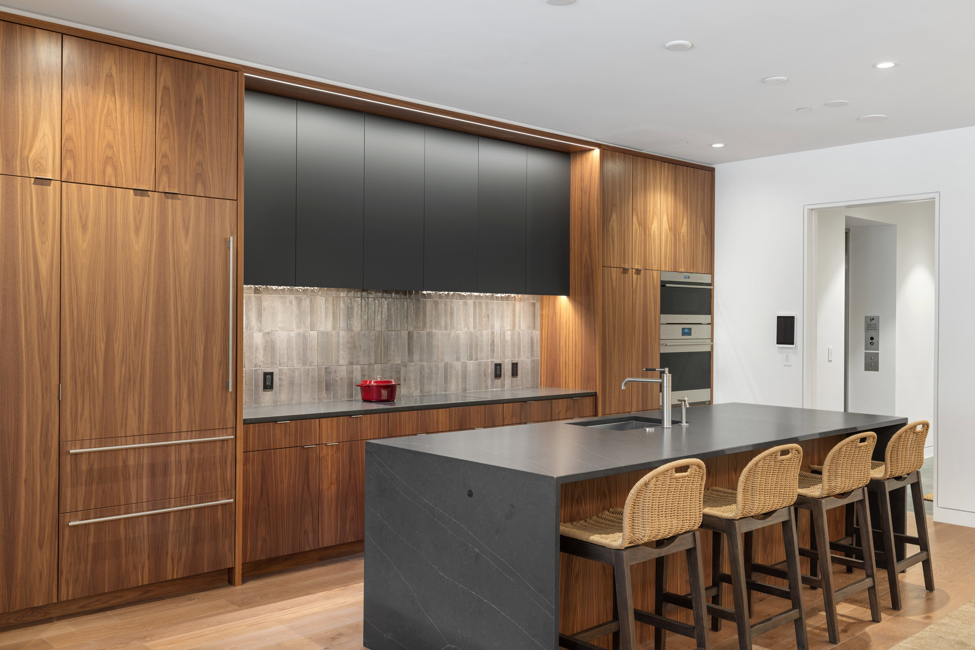 Modern kitchen featuring wood-finish cabinetry, integrated refrigerator, and a large center island with a sink