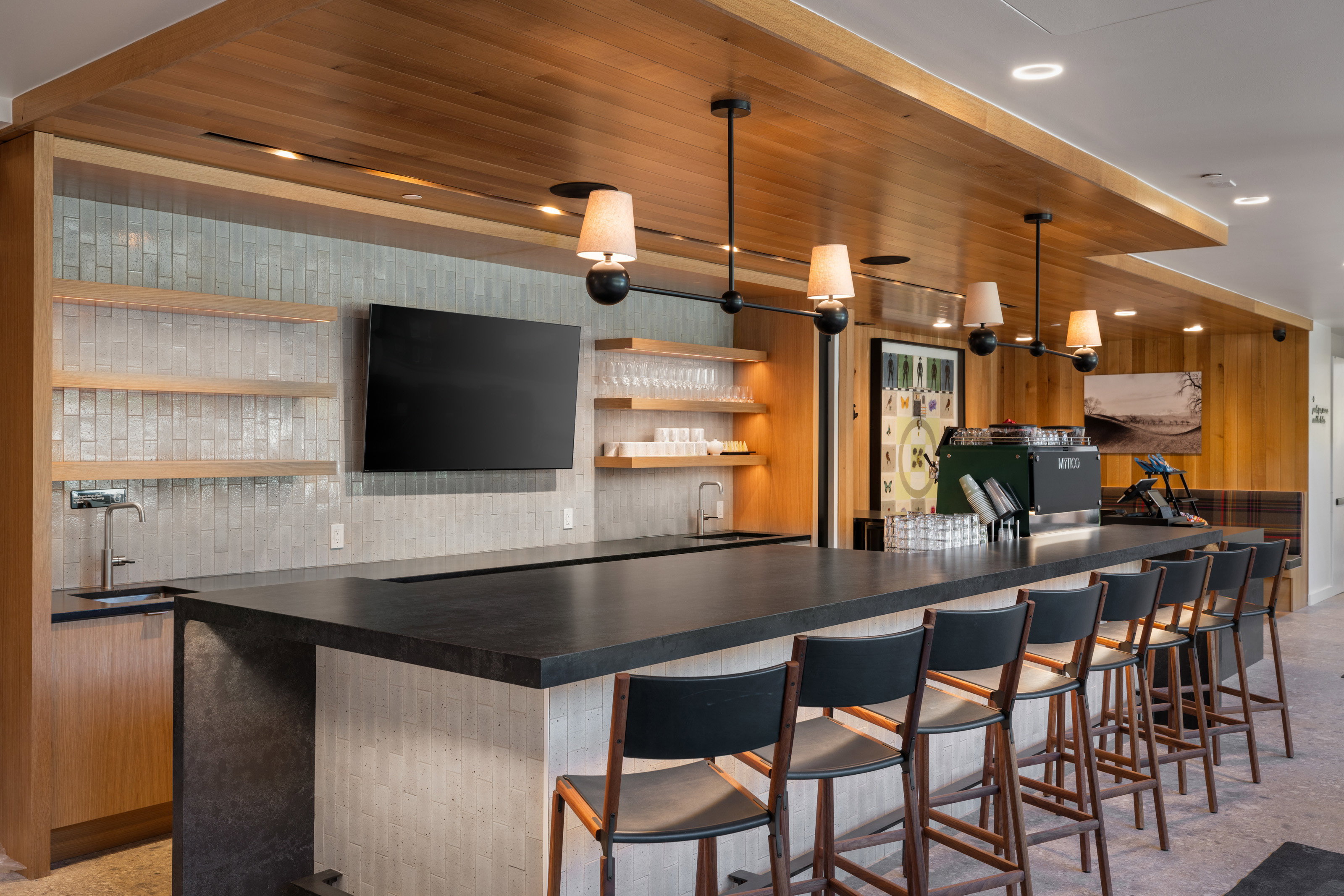 Expansive wet bar featuring a black countertop, wood-finish ceiling, and textured tile backsplash