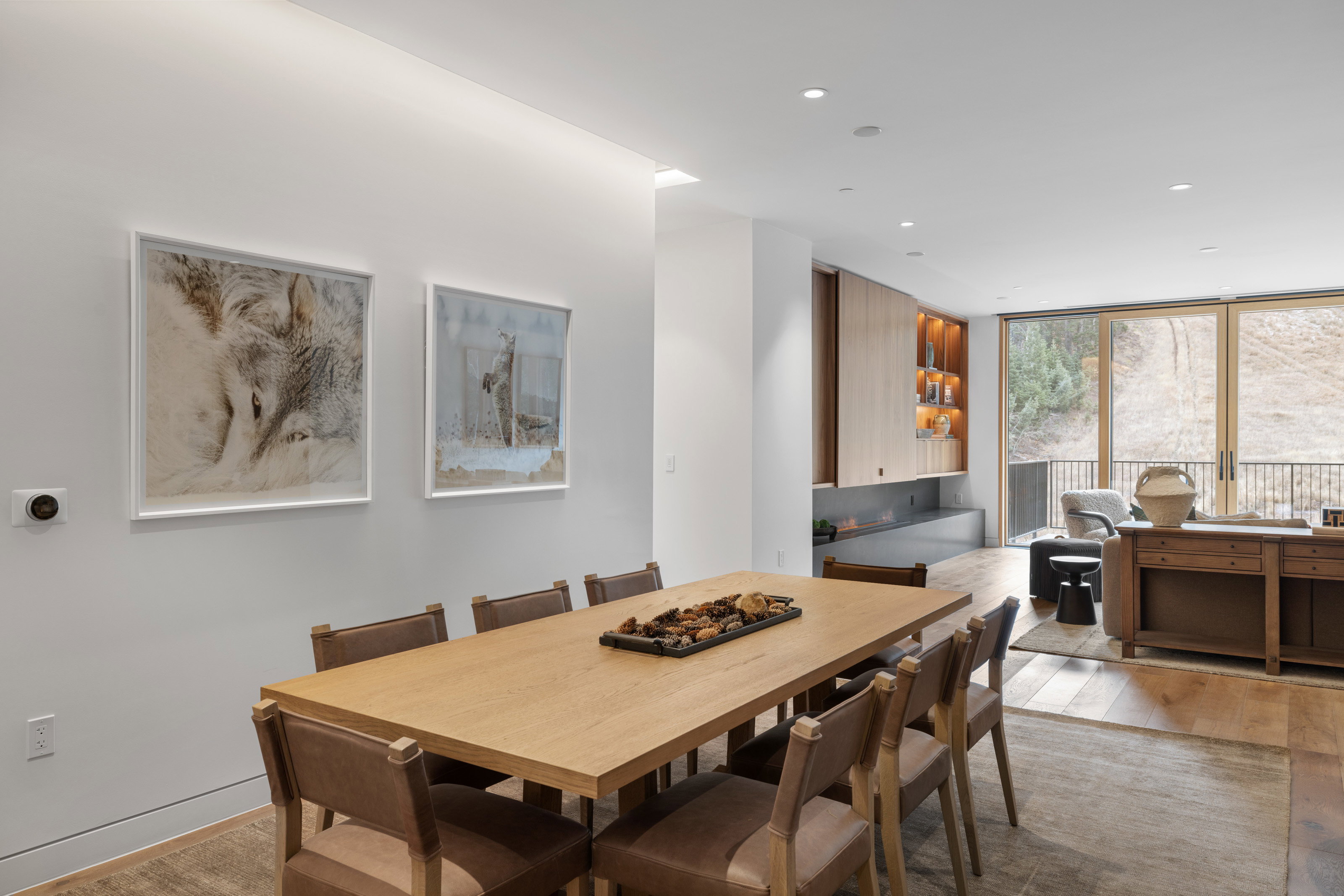 Open-concept dining area featuring wood-finish flooring, recessed lighting, and a modern built-in fireplace with integrated shelving