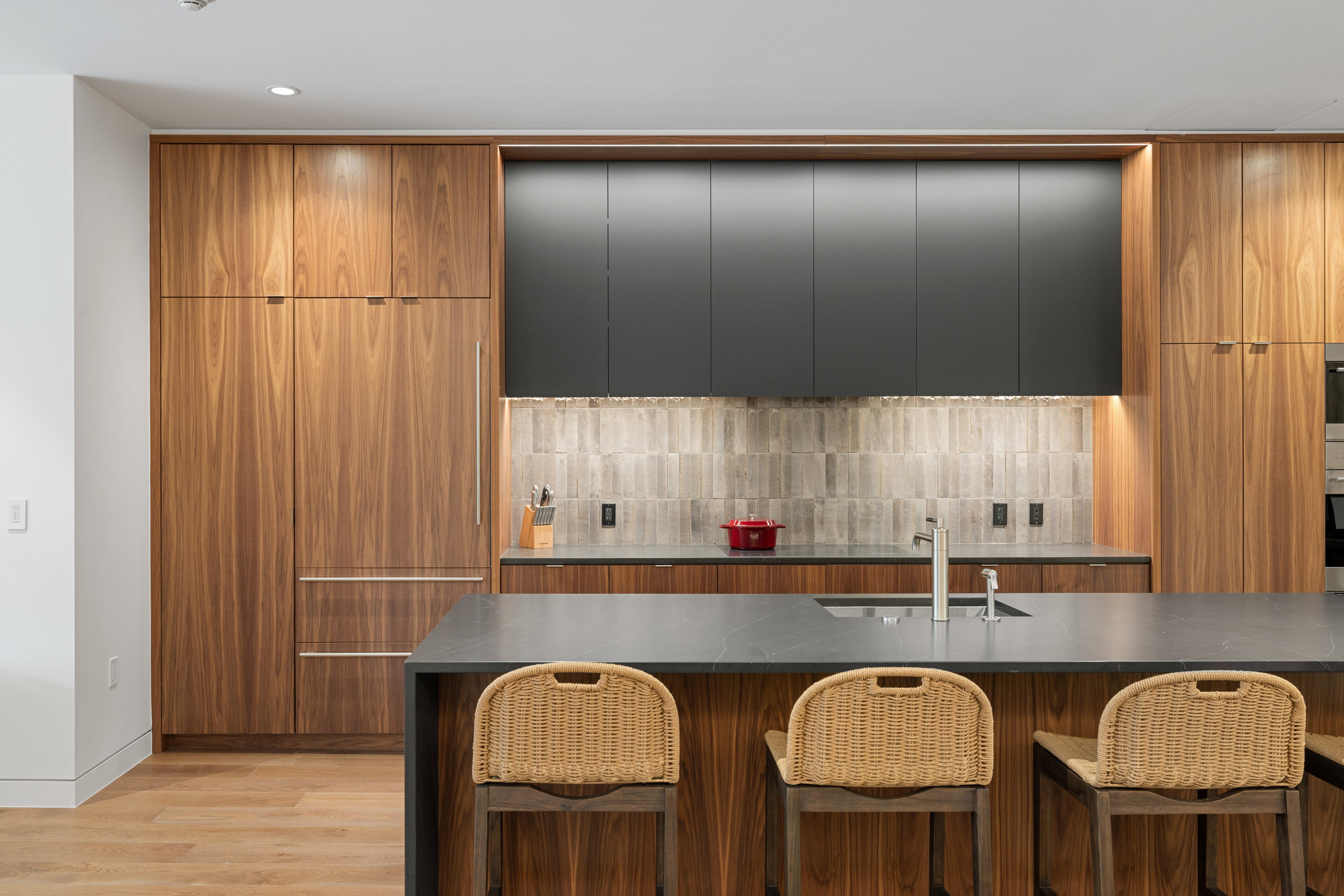 Contemporary kitchen featuring rich wood-finish cabinetry and a dark stone countertop island