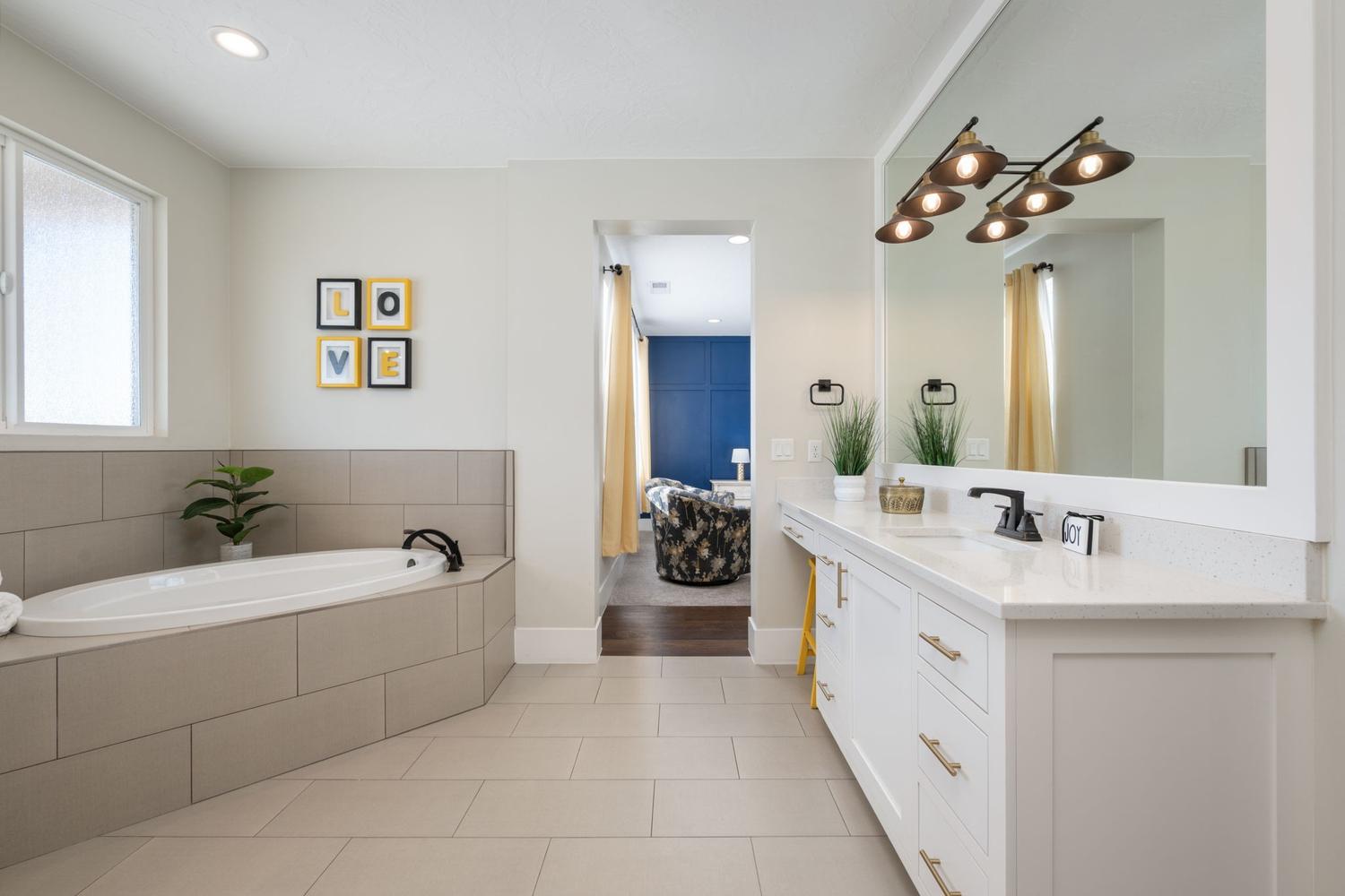 Contemporary bathroom featuring a built-in soaking tub, a dual vanity with a quartz countertop, and a large wall-mounted mirror