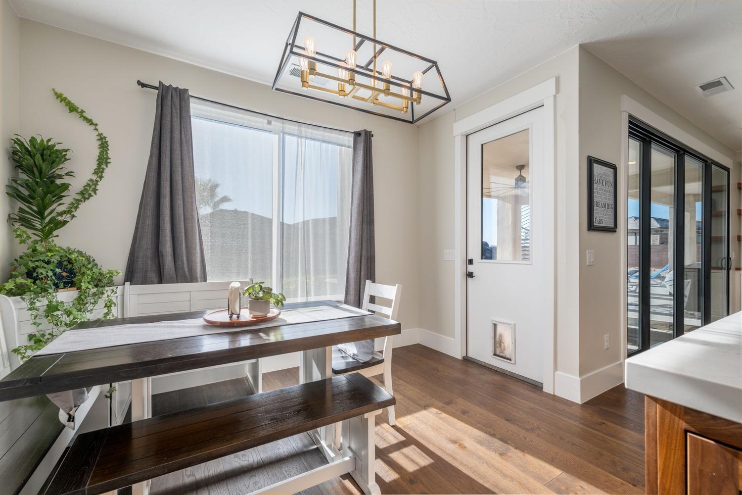 Dining area with wood-finish flooring and a contemporary linear chandelier