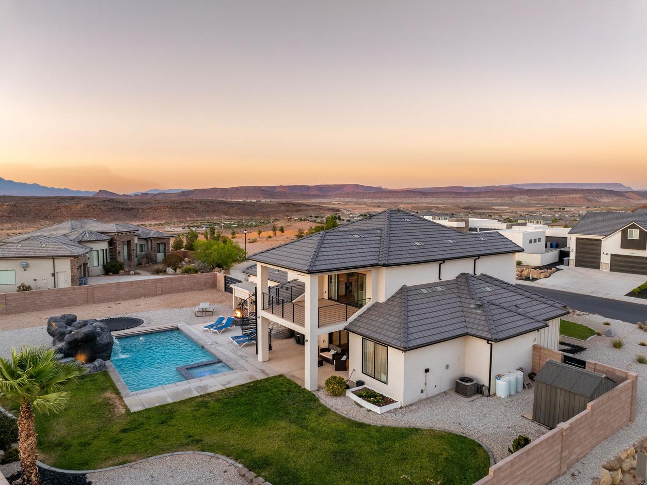 Expansive backyard featuring a rectangular swimming pool with integrated spa, a trampoline, and a structured water feature