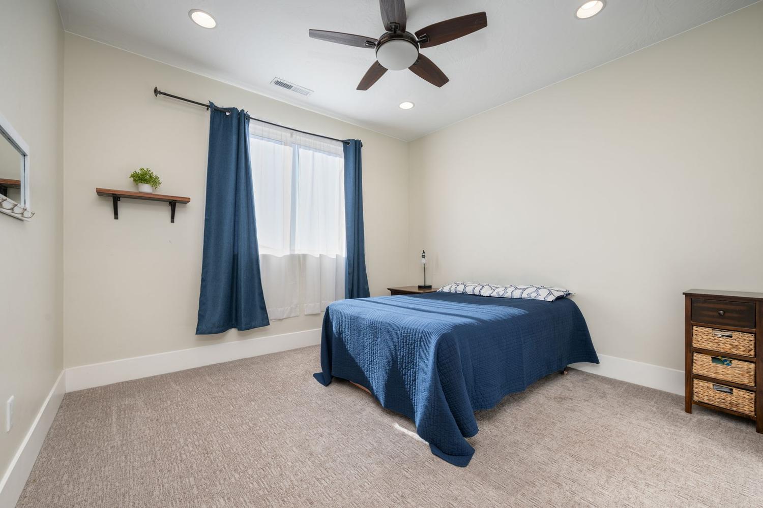 Carpeted room featuring a ceiling fan with integrated lighting, recessed lighting, and a large window with privacy sheers