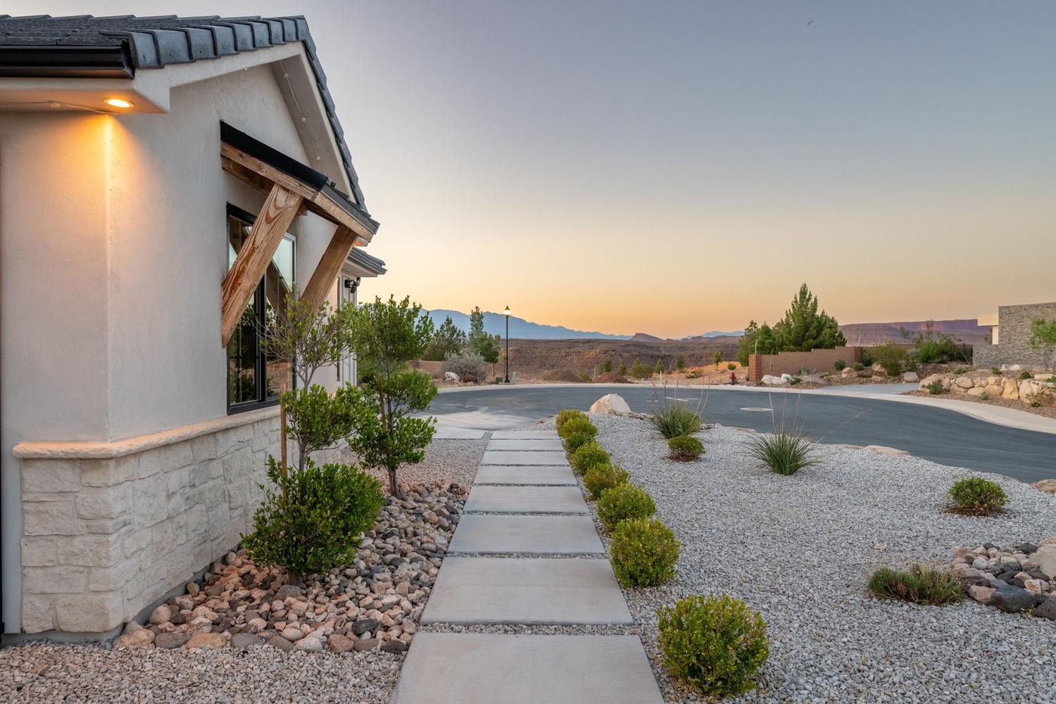 Contemporary exterior featuring a stucco finish with stone veneer accents, a dark tile roof, and a wood-bracketed window awning