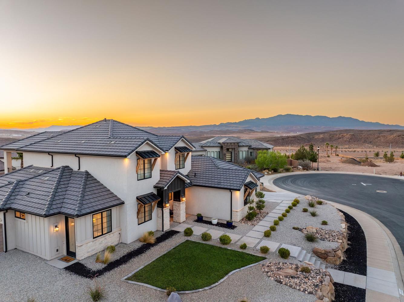 Contemporary stucco home featuring a dark tile roof, black-framed windows, and stone accents