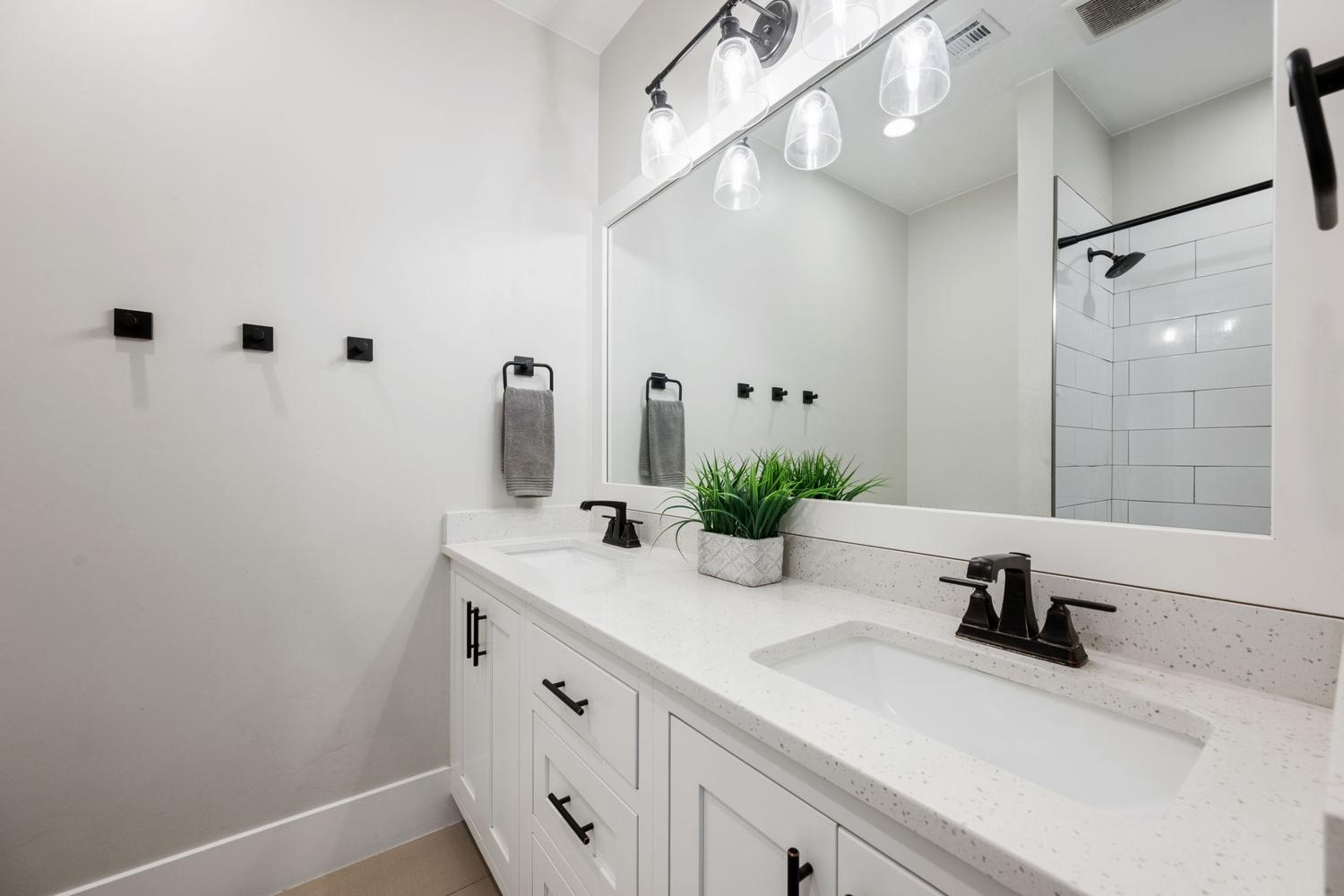 Dual vanity with white cabinetry and integrated sinks, complemented by dark-finish hardware and faucets