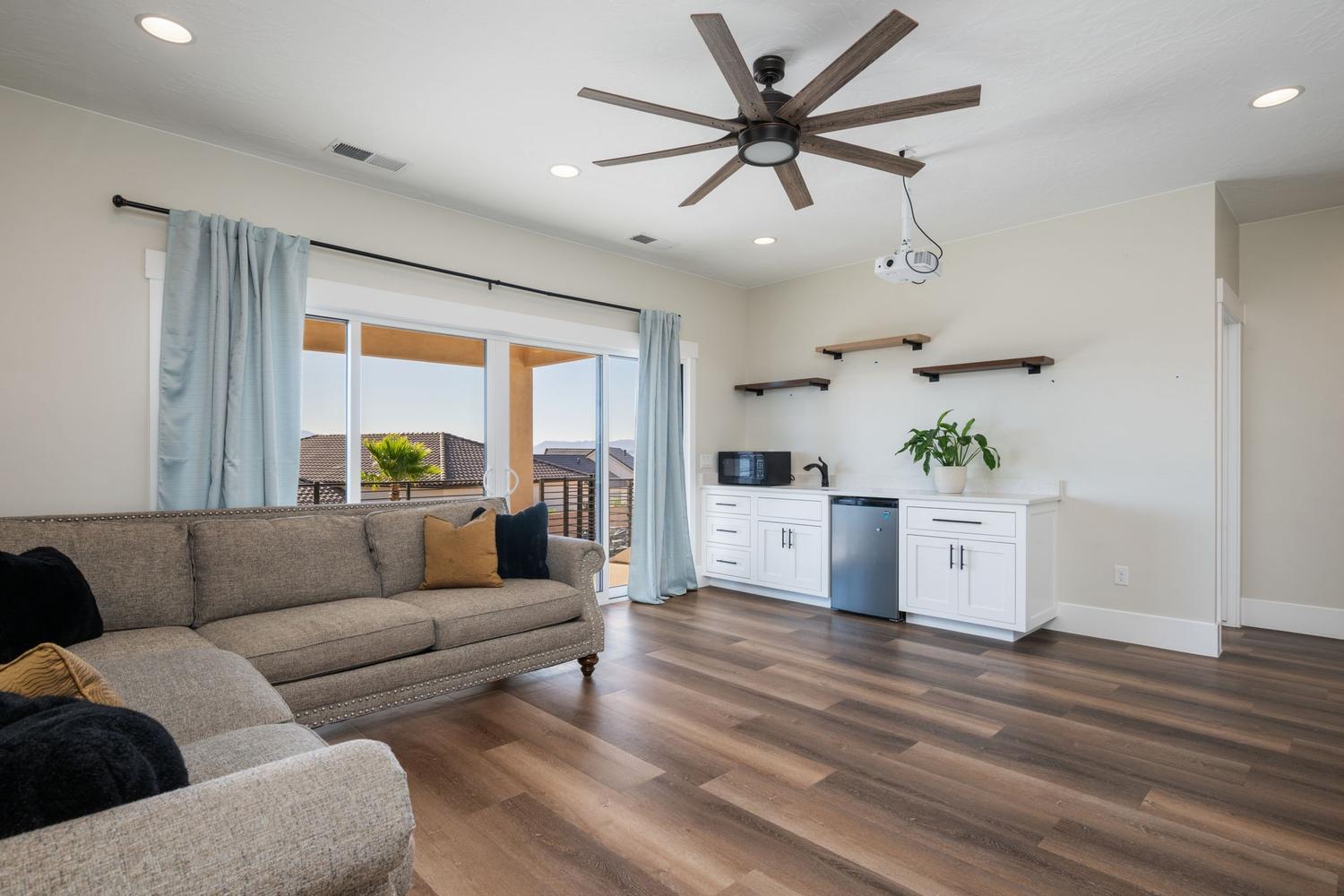 Spacious entertainment room featuring wood-finish flooring and a ceiling fan