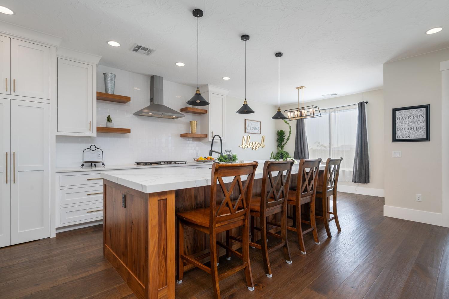 Kitchen featuring a wood-finish island with seating, white shaker cabinetry, stainless steel range hood, white subway tile backsplash, and dark wood-finish flooring