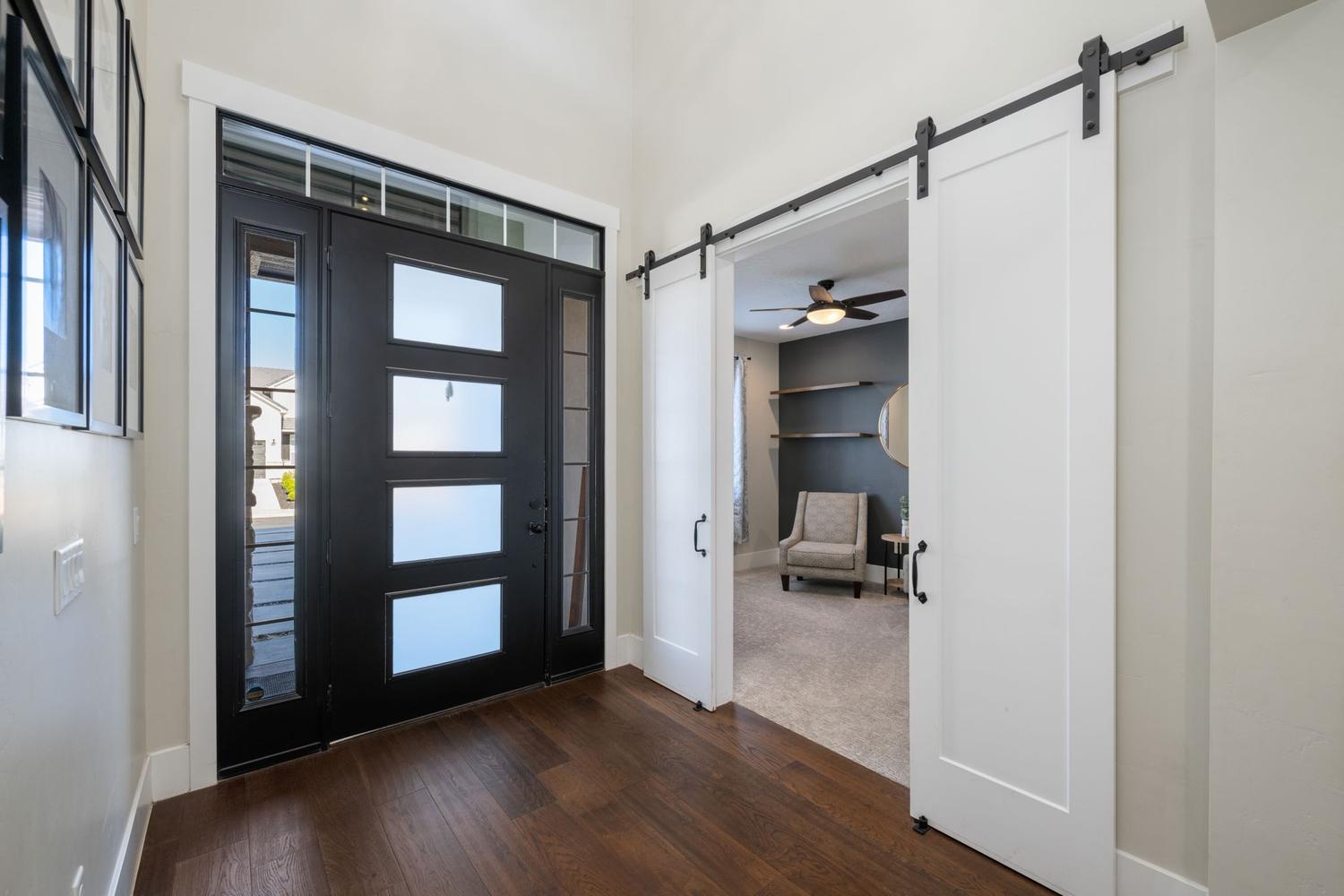 Entryway featuring a modern black door with frosted glass panels, wood-finish flooring, and a sidelight window