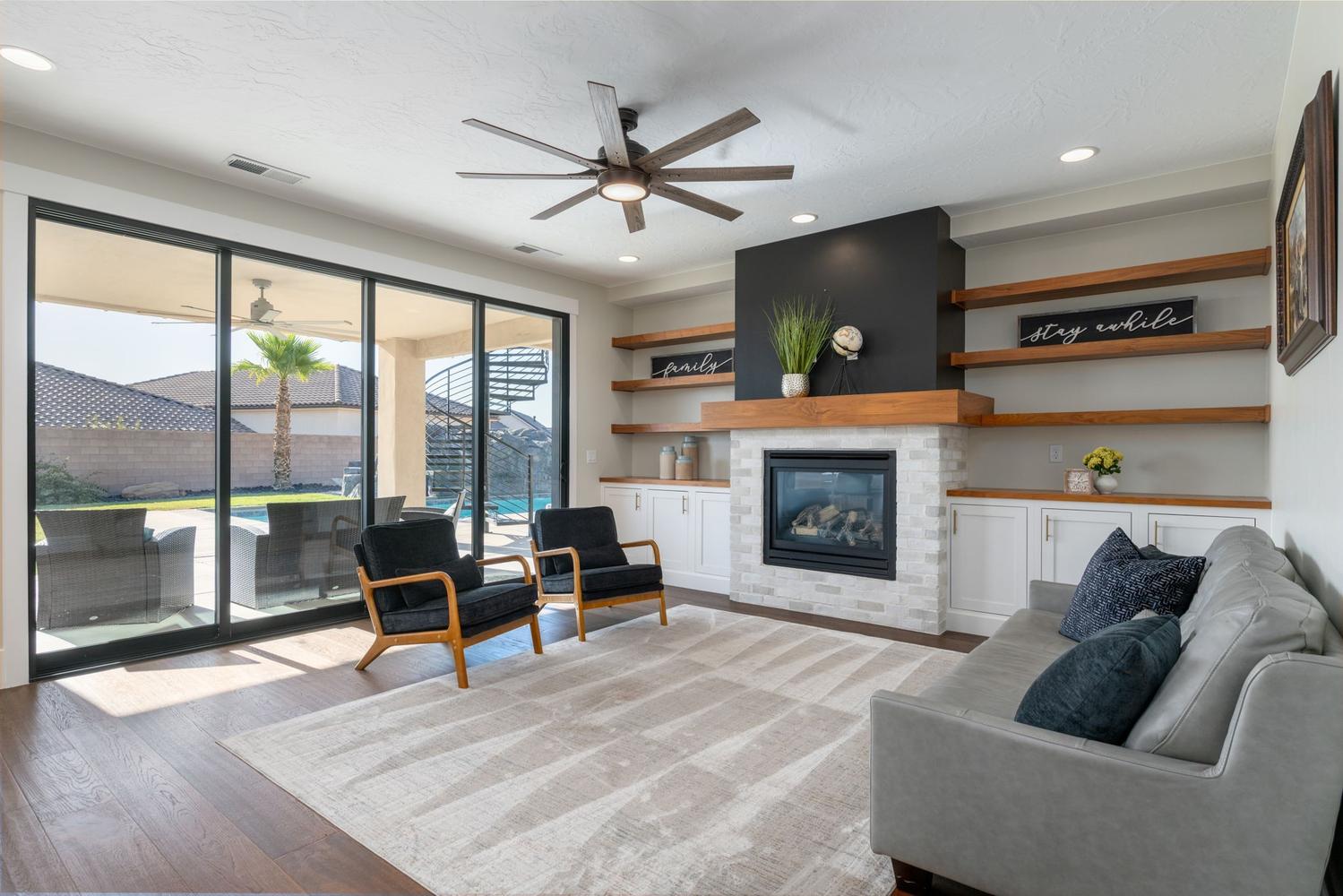 Living area featuring a floor-to-ceiling fireplace with a white brick surround and wood mantel, built-in cabinetry with wood countertops, and wood-finish open shelving