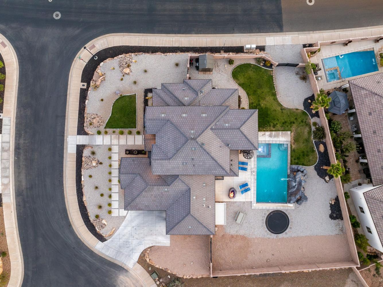 Expansive property featuring a multi-gabled roofline, a curved driveway, and a rectangular swimming pool with an adjacent rock waterfall feature
