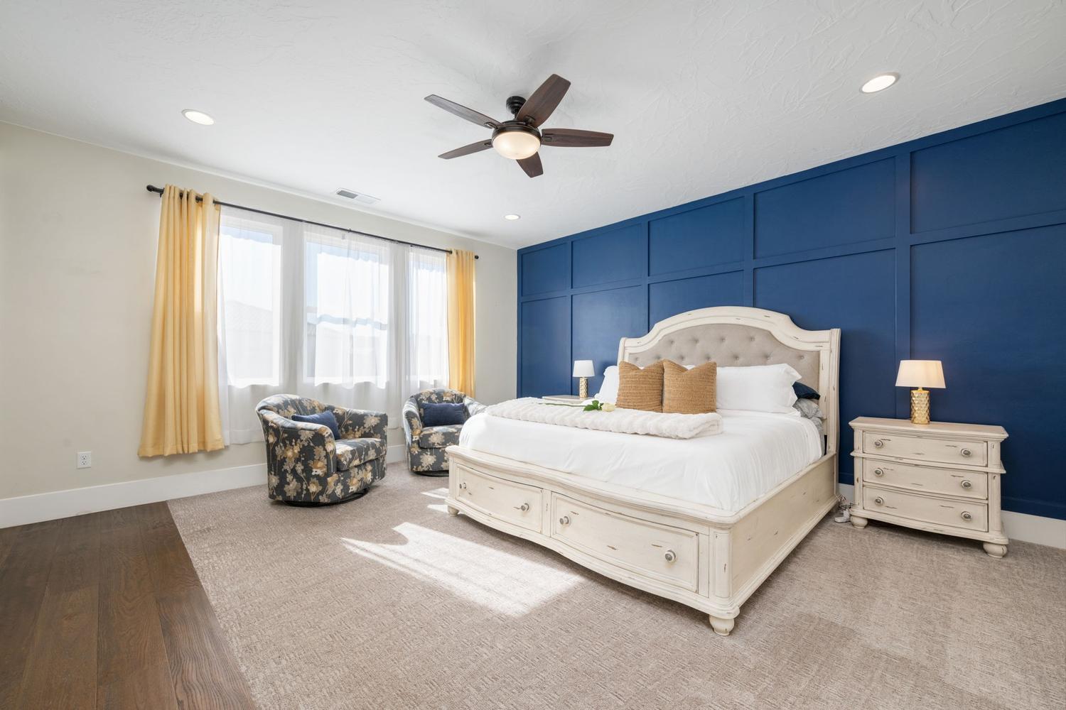 Spacious room featuring a prominent blue accent wall with paneling, multiple windows, recessed lighting, and a ceiling fan